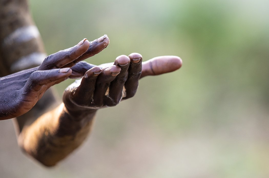 close up of hands of Mursi tribe boy painting his body