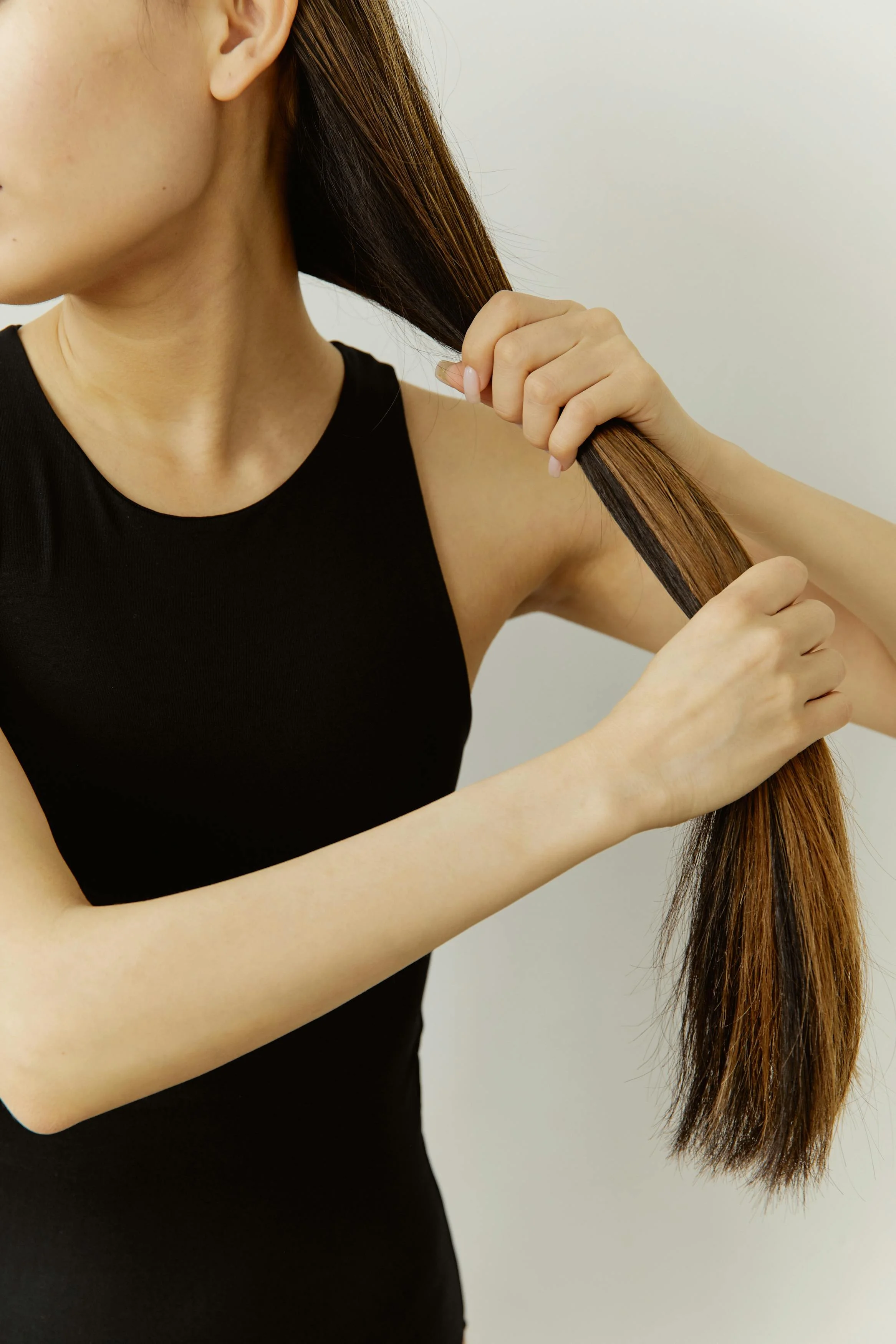 Hands holding long hair to assess dryness and breakage — inspiration for scalp therapy and hair health services at Cosmic Beauty in Kapolei