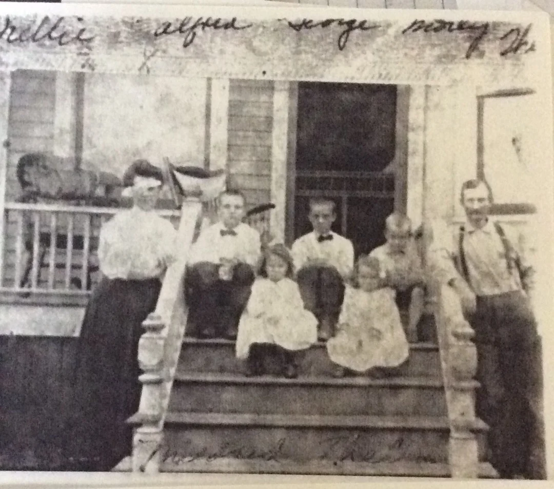 Thelma (front row on the right) sitting with 4 of her siblings, flanked by their parents, Nelllie and James. The boys (left to right) are: Alpheus, George, and Morely. Mildred is next to Thelma. Likely at their home on Baldwin St. in Detroit, MI.