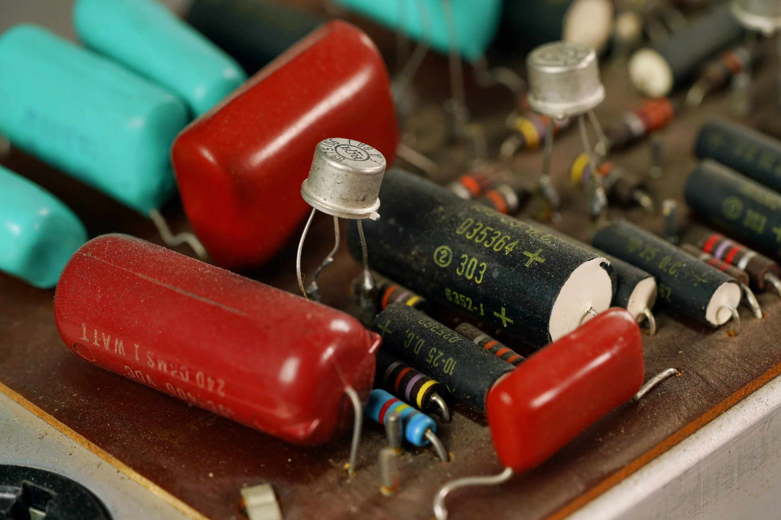 A closeup of a transistor on a brown printed circuit board,