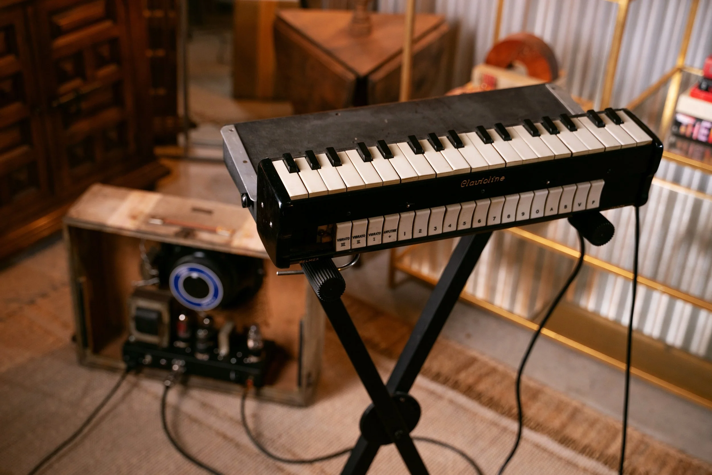 A Clavioline keyboard on a keyboard stand, with its amplifier in the background.