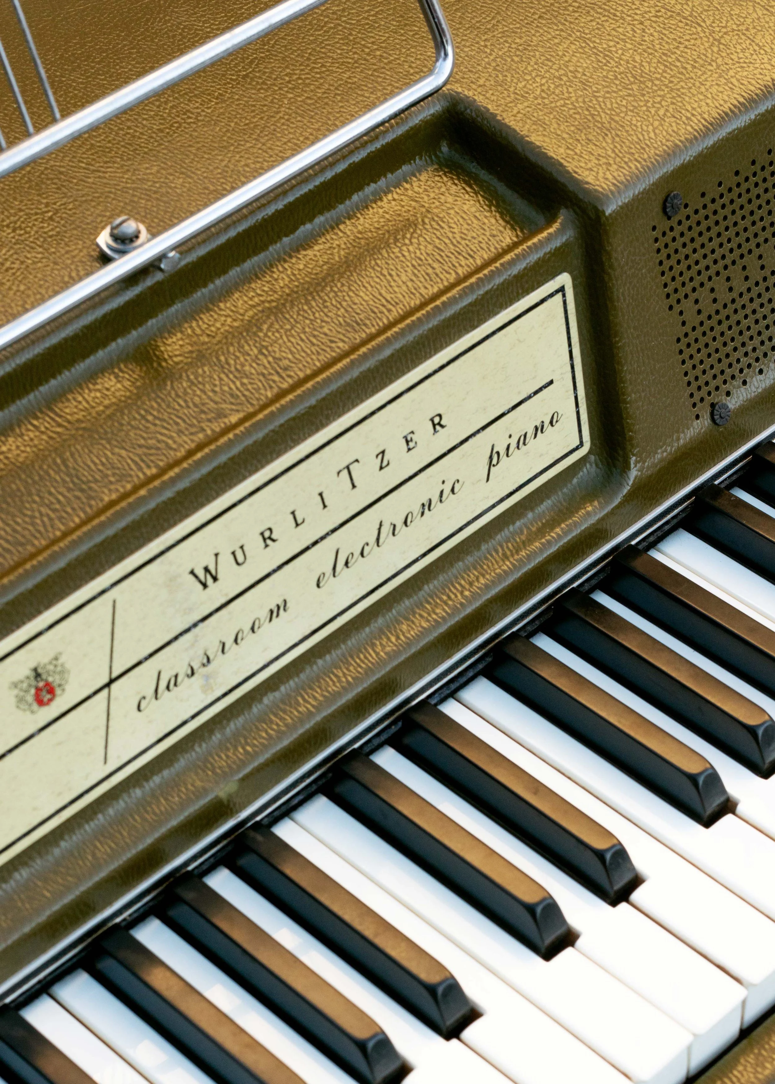 A closeup of a Wurlitzer 200A in avocado green showing the faceplate and the middle register of keys.