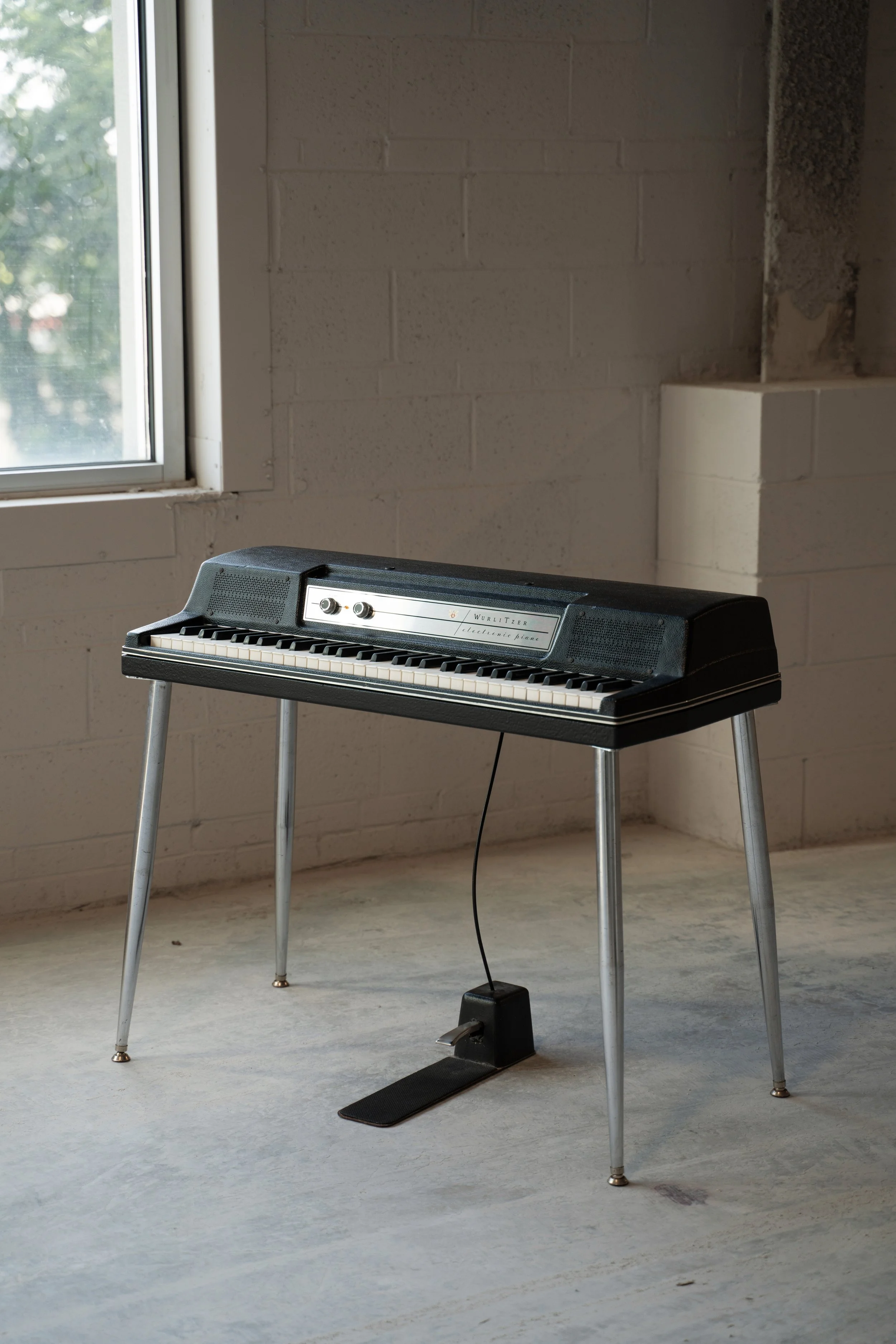 Wurlitzer 200A in room with white cinderblock walls and a large window.