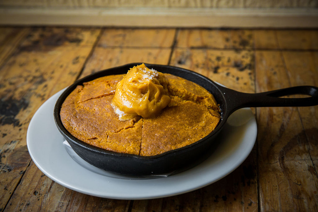  Cast iron cornbread topped with Three Brothers Cane Syrup Butter, a menu item of walk-in restaurant Sylvain in New Orleans, LA 