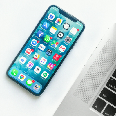 Smartphone Next to Laptop with Mobile Apps on Its Screen