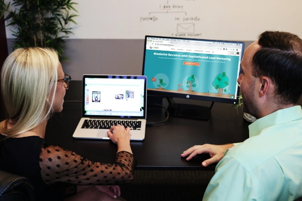 Project Manager Using Her Laptop to Discuss Her Client’s Web Design Project with Him