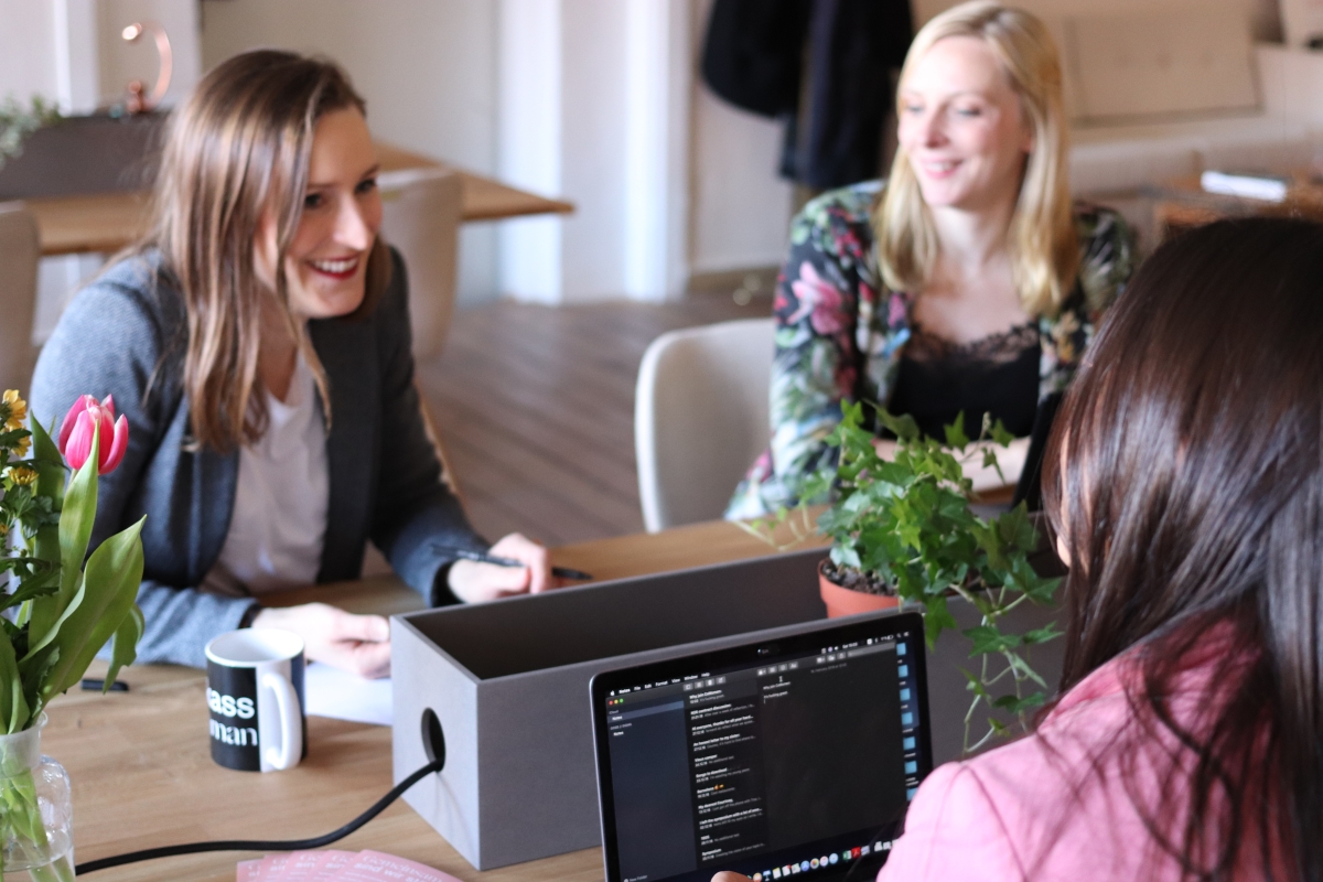 Two Female Project Managers Sitting at a Table and Speaking with Their Female Client