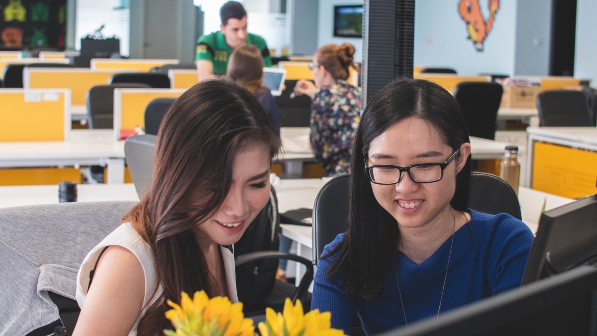 Female Scrum Master Working with a Female Software Developer at Her Desk
