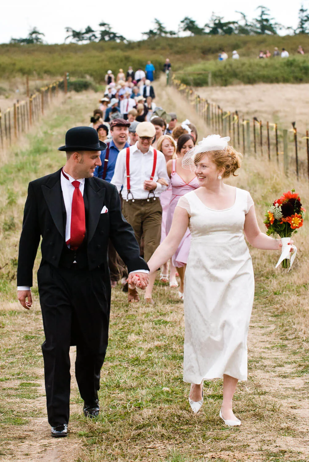 bride-groom-lead-guests-field-wedding.jpg