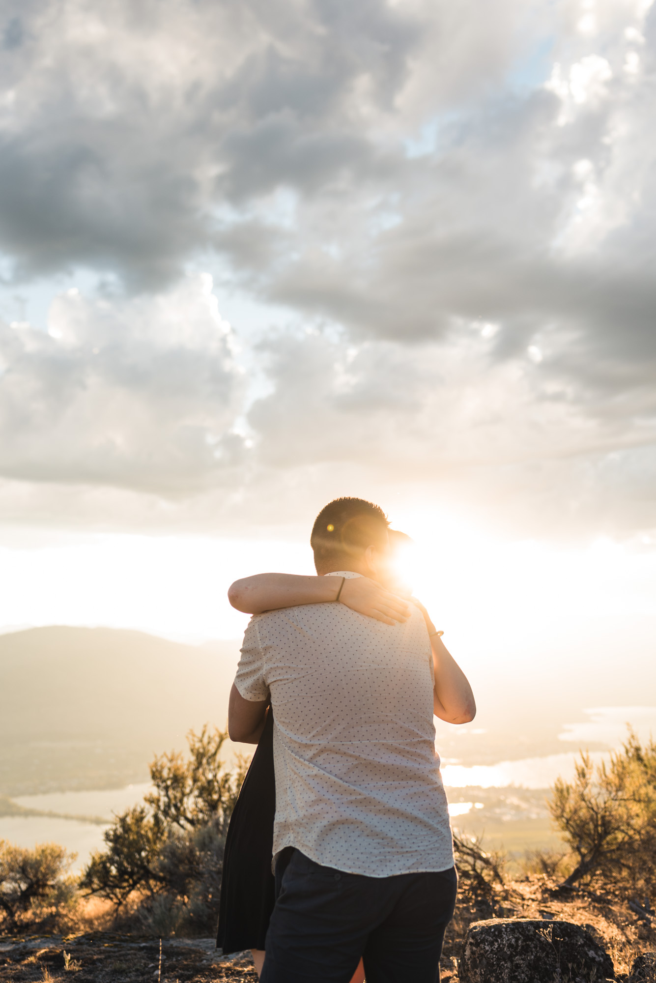Engaged couple embraces with sunset on Anarchist Mountain, Osoyoos