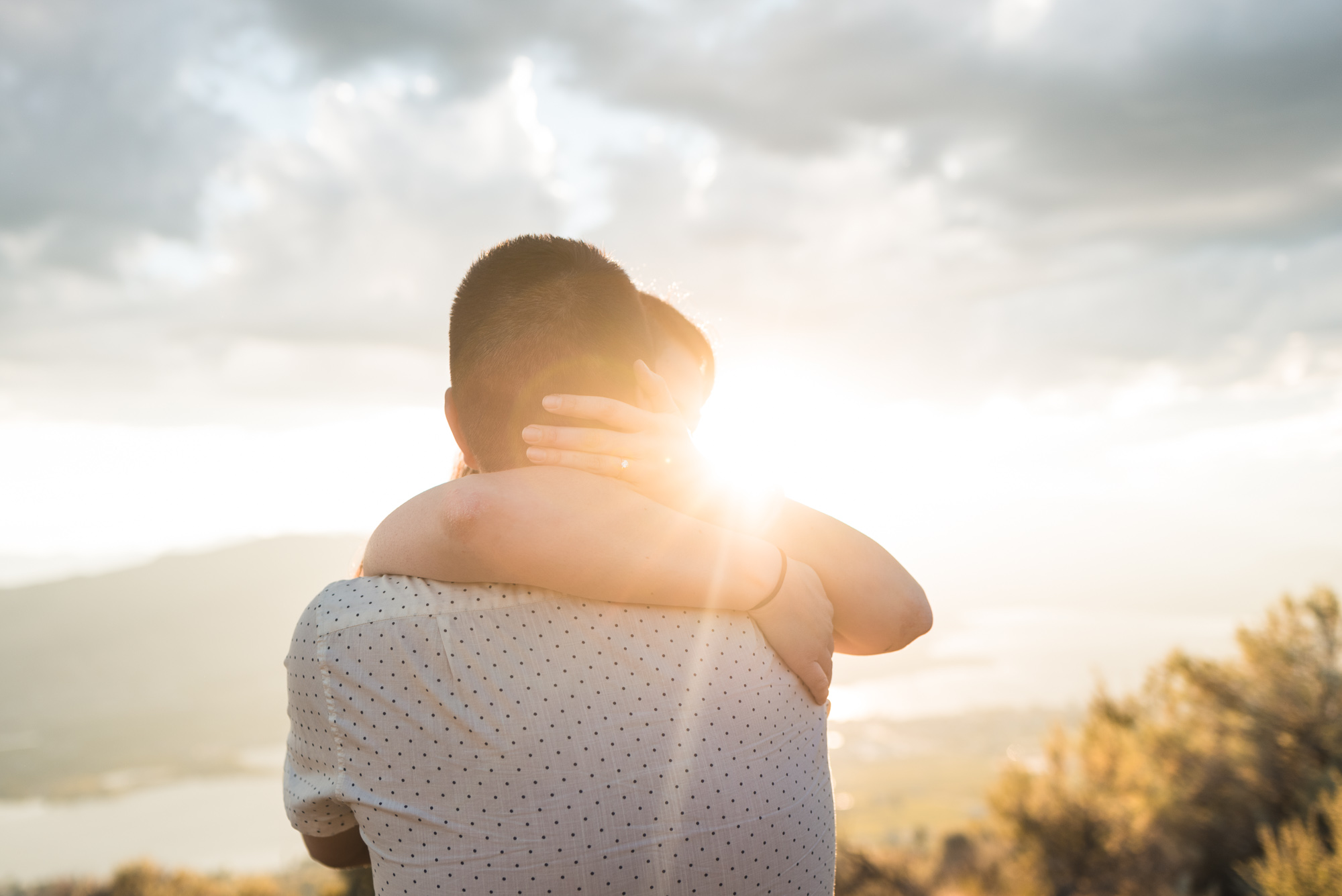 Engaged couple embraces with sunset on Anarchist Mountain, Osoyoos