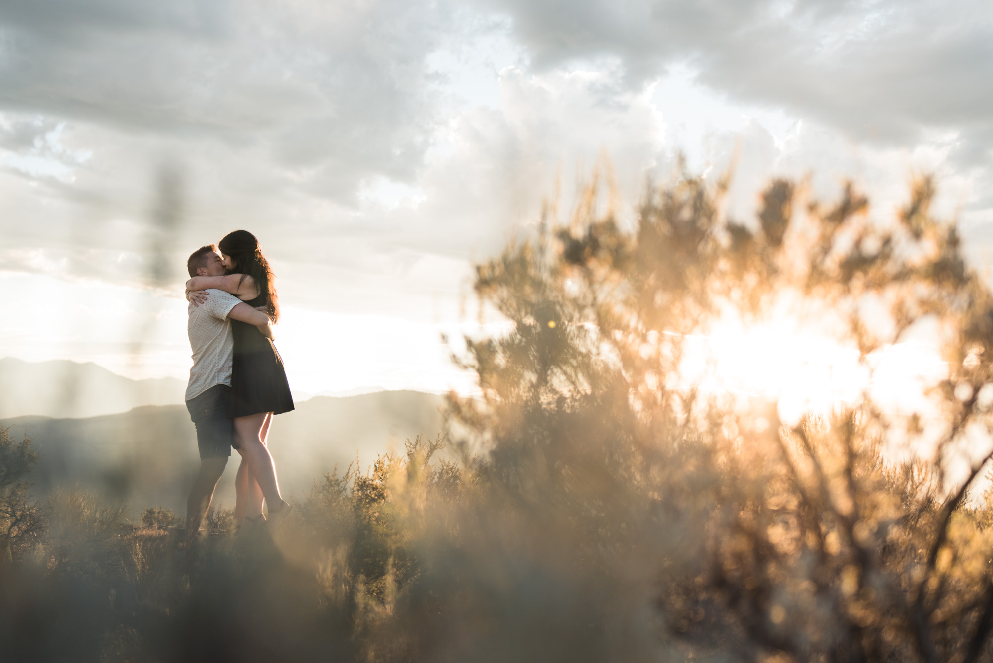 Engaged couple embraces with sunset on Anarchist Mountain, Osoyoos
