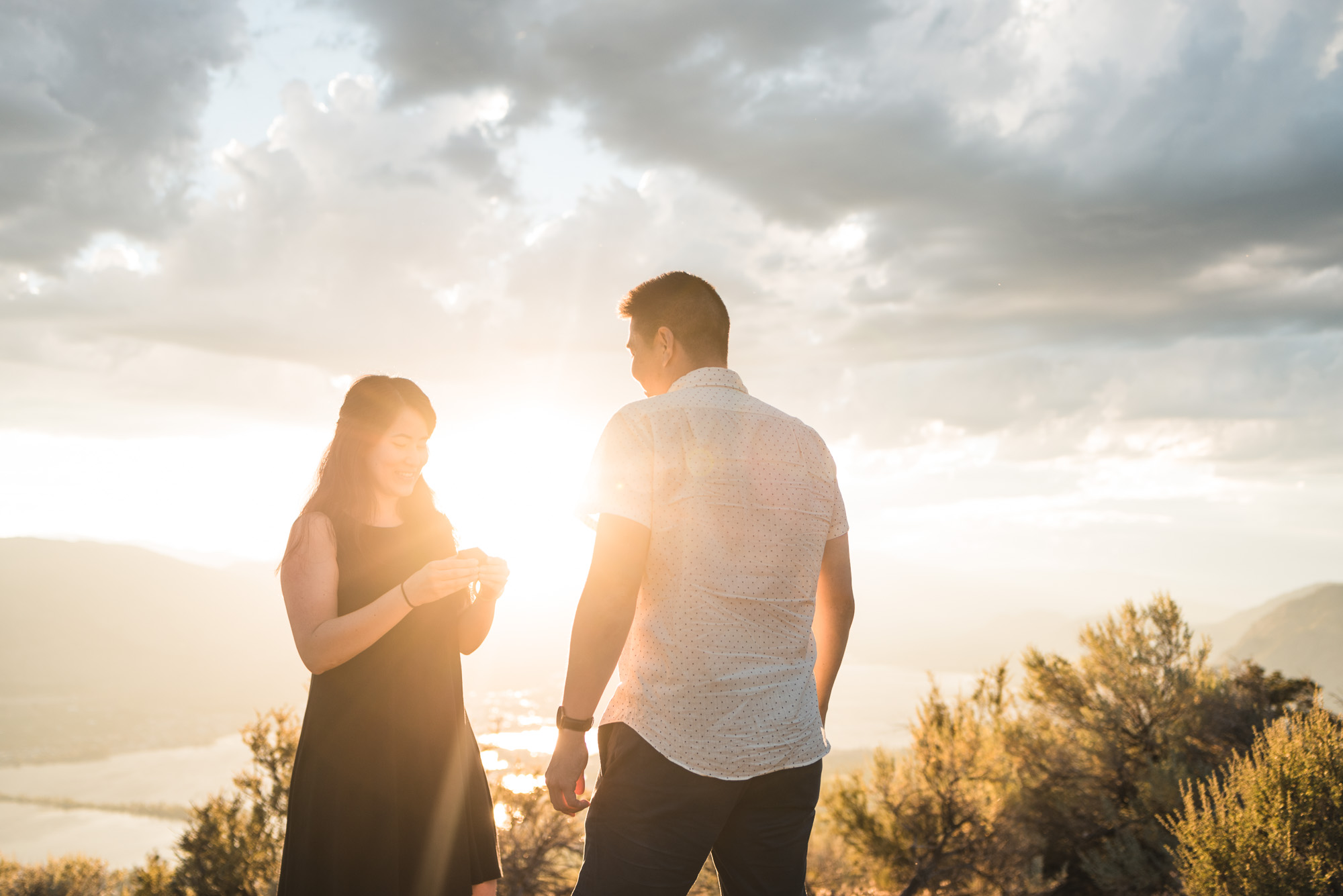 Engaged couple looks at ring with sunset on Anarchist Mountain, Osoyoos