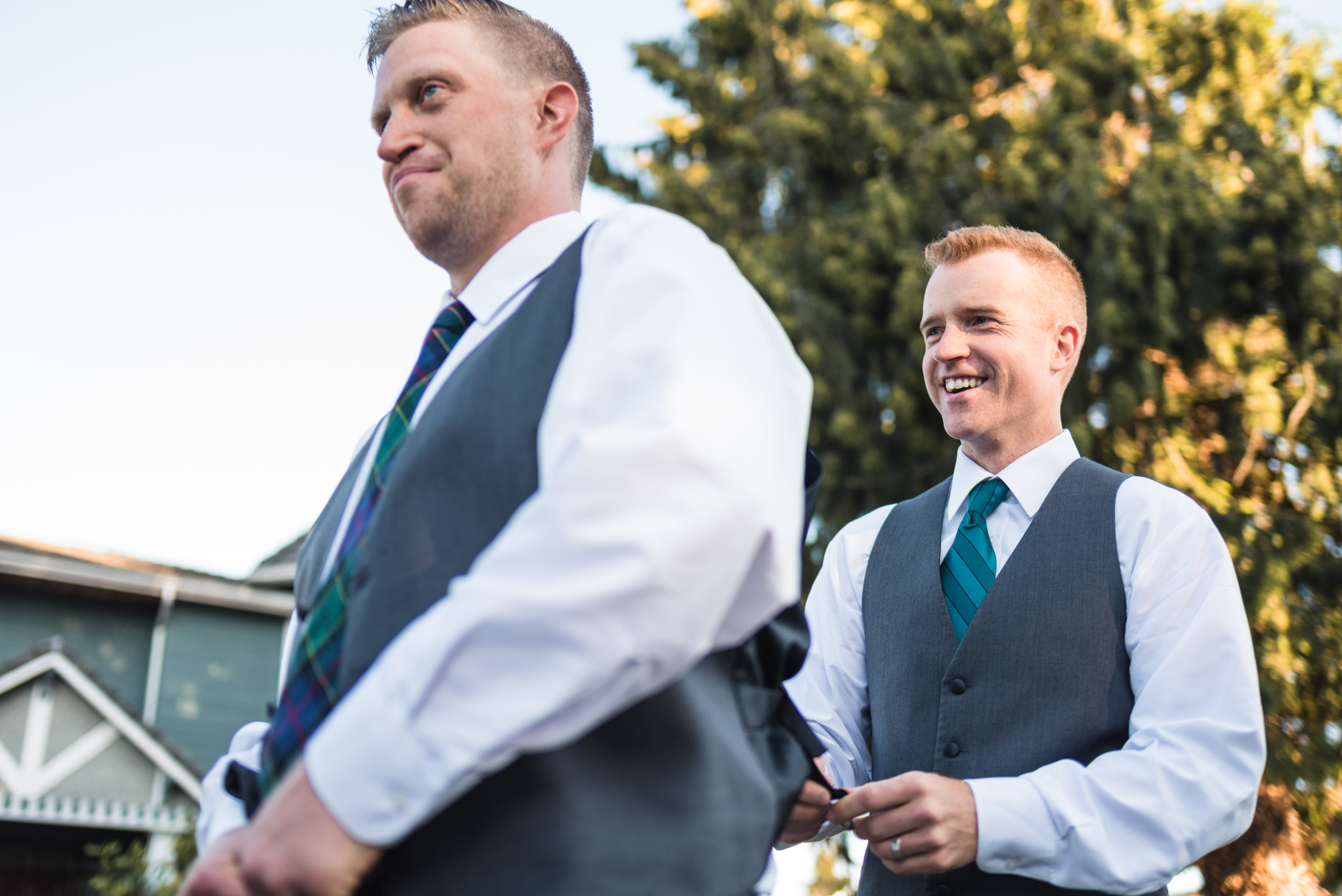 Groomsman helping groom get dressed