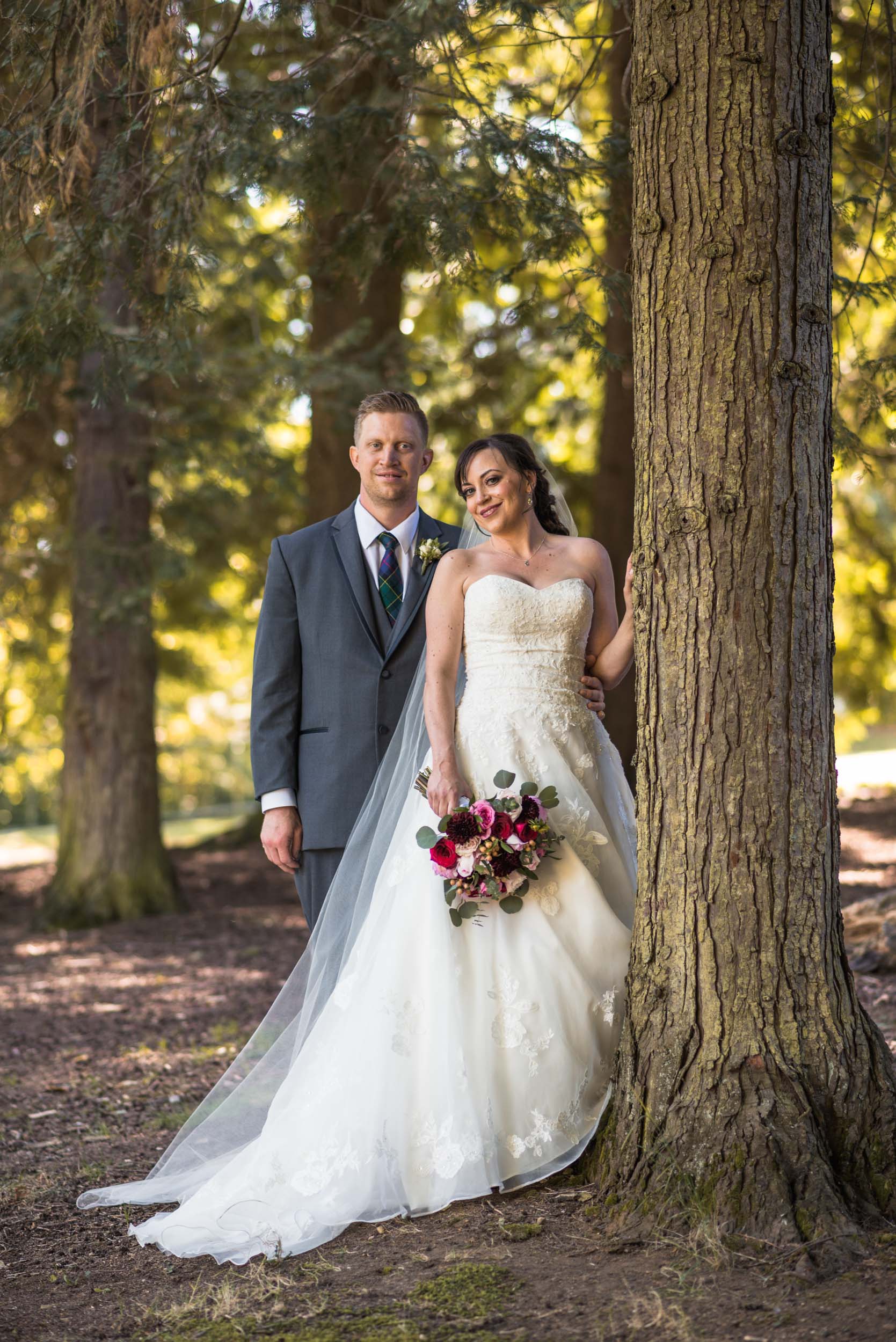 Bride and Groom leaning on tree