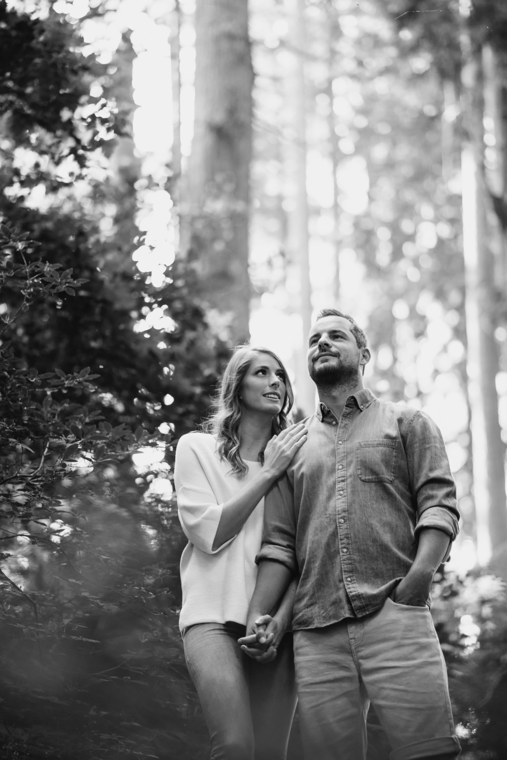 Couple looks off into the distance in the forest