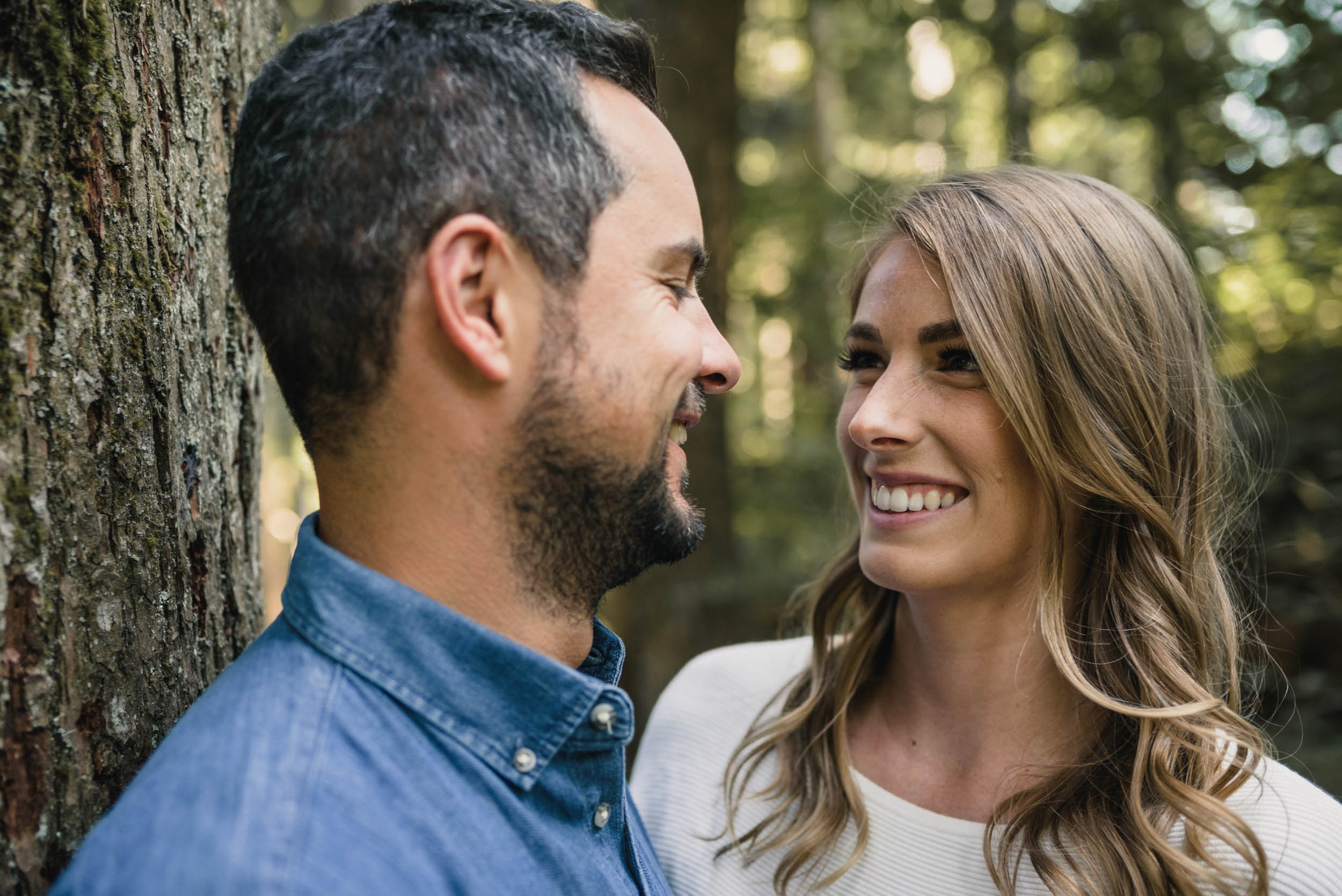 Couple smiles at each other in the forest