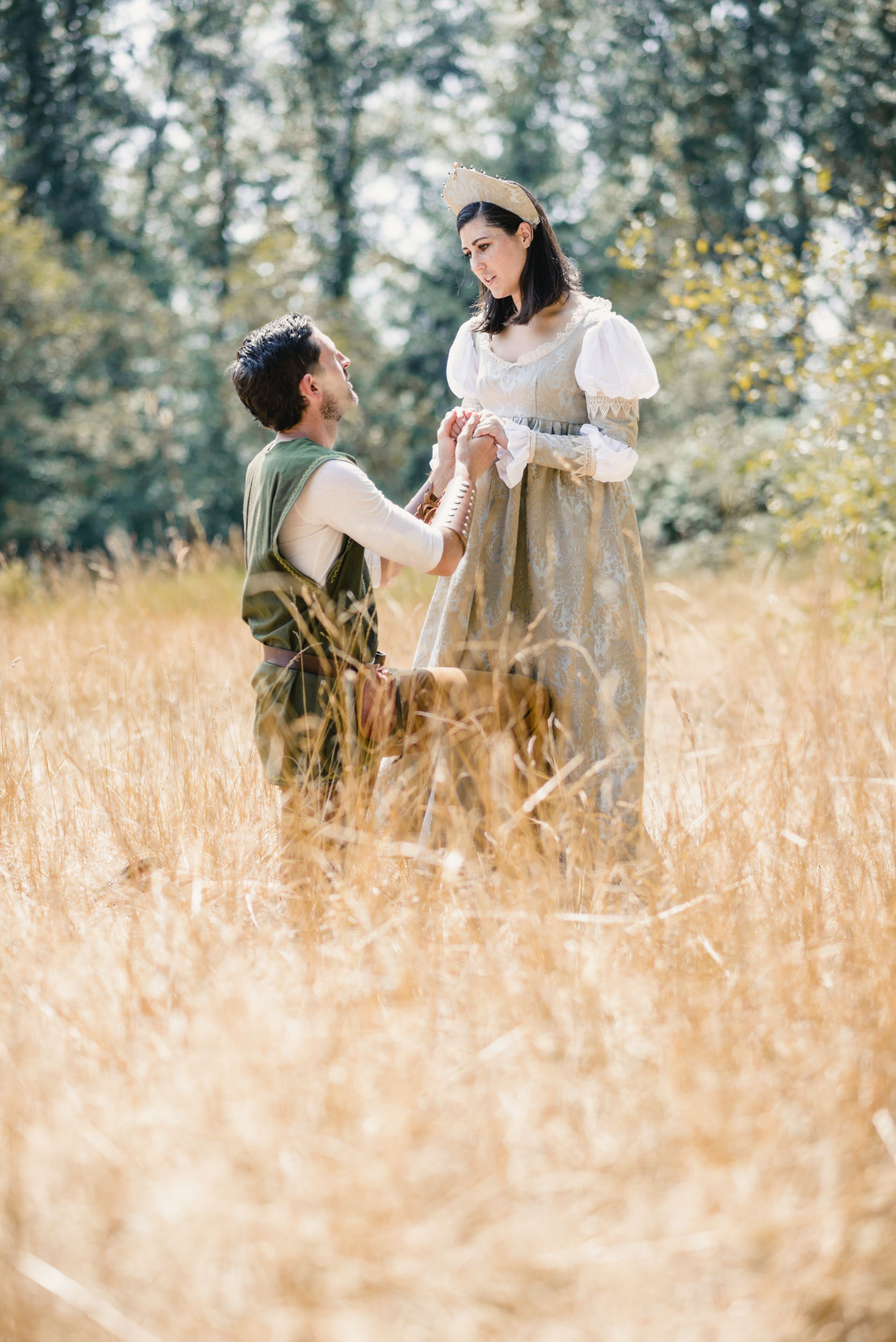 Couple kneeling in field with medieval costumes