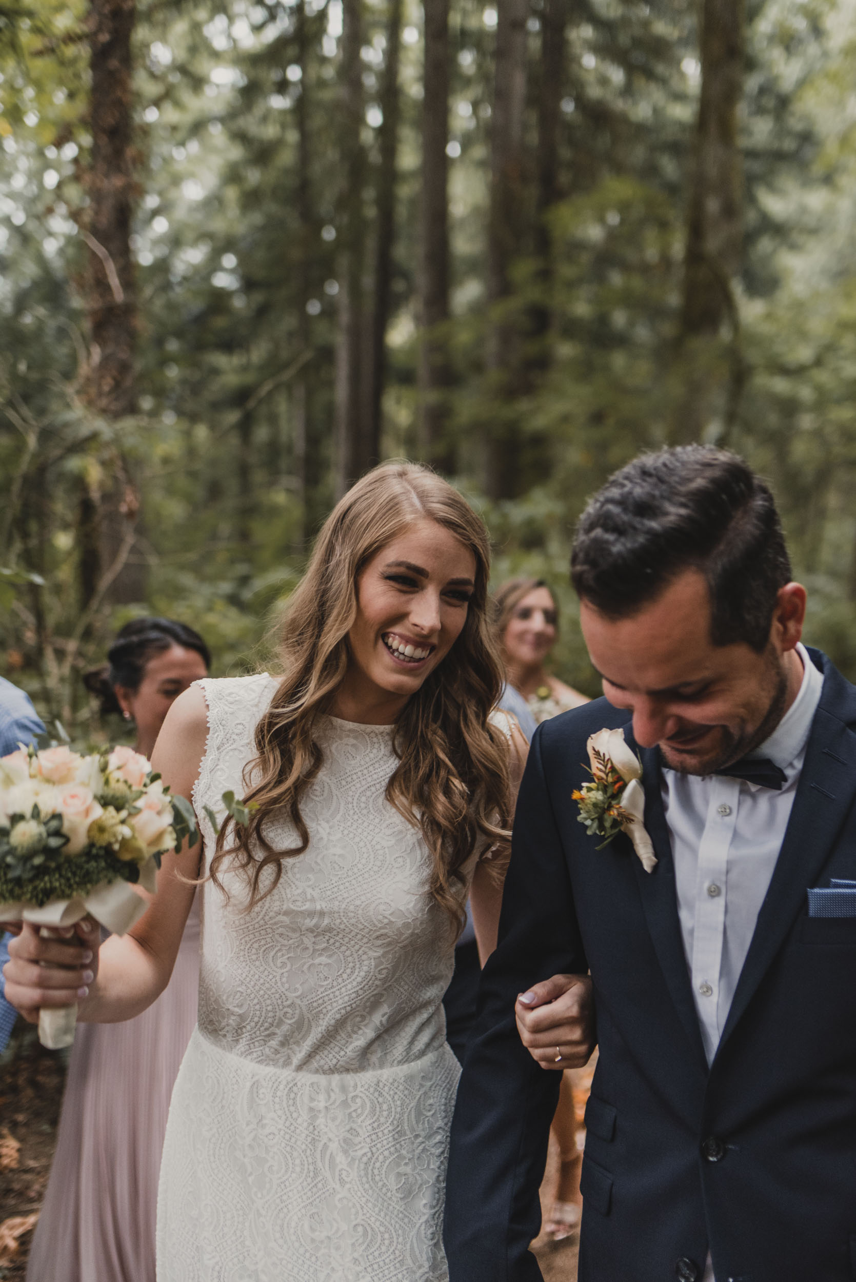 Bride and groom walk through forest