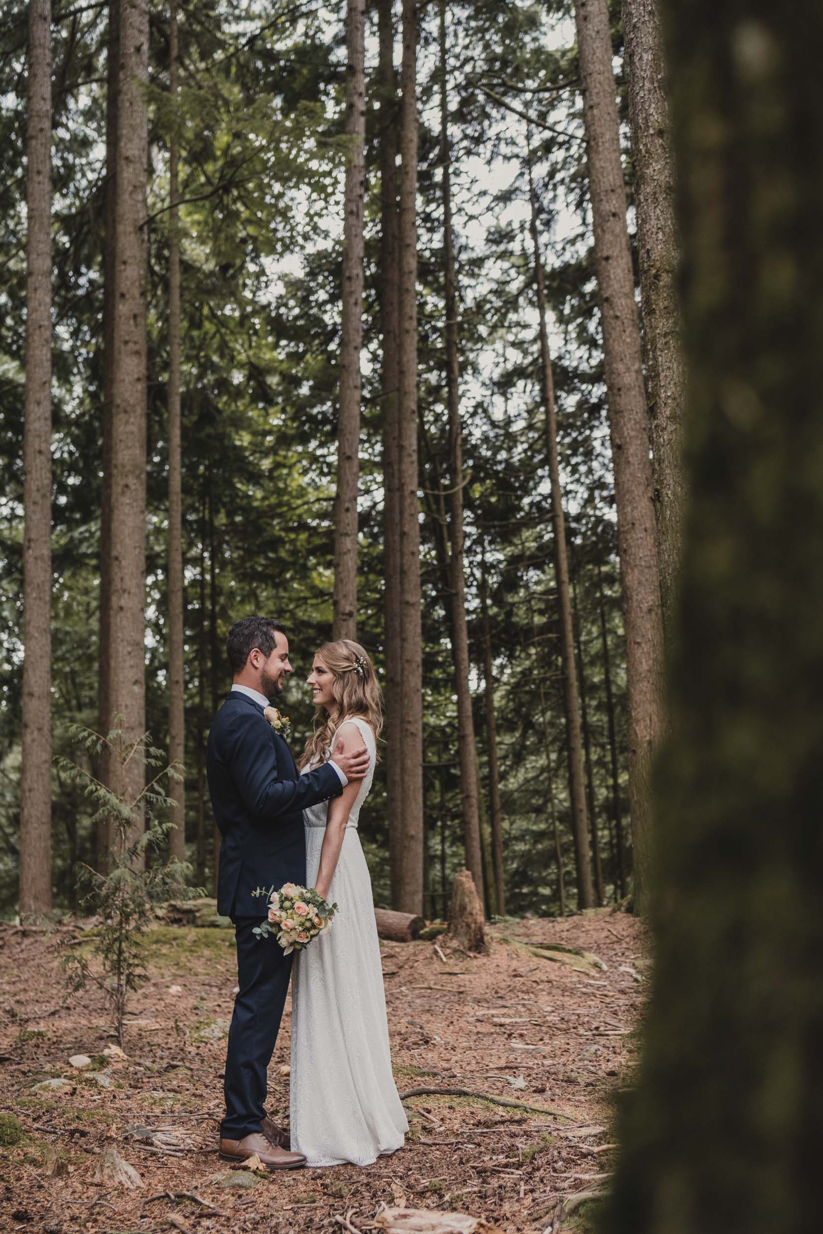 Bride and groom embrace in forest