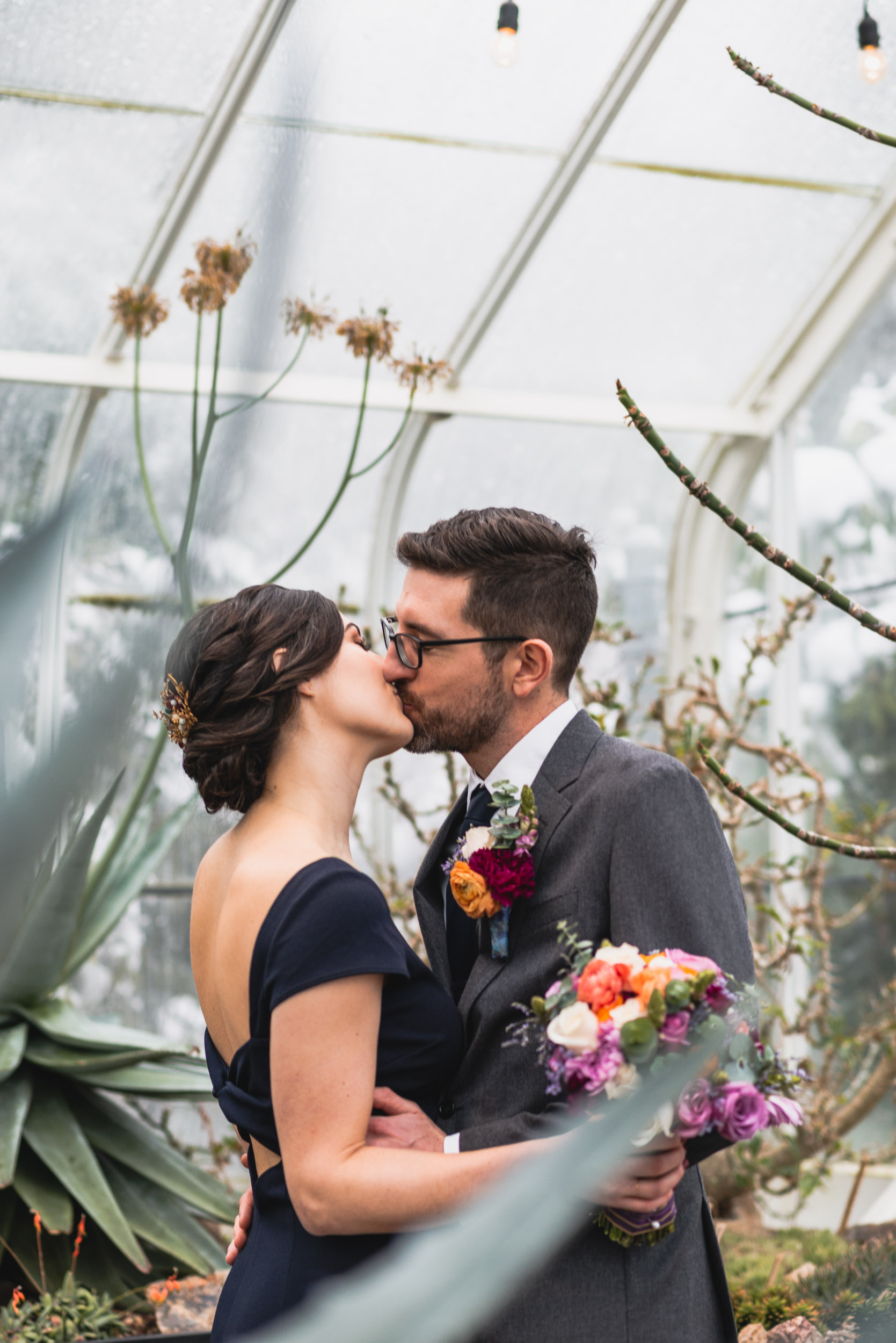 Bride and groom kiss among plants