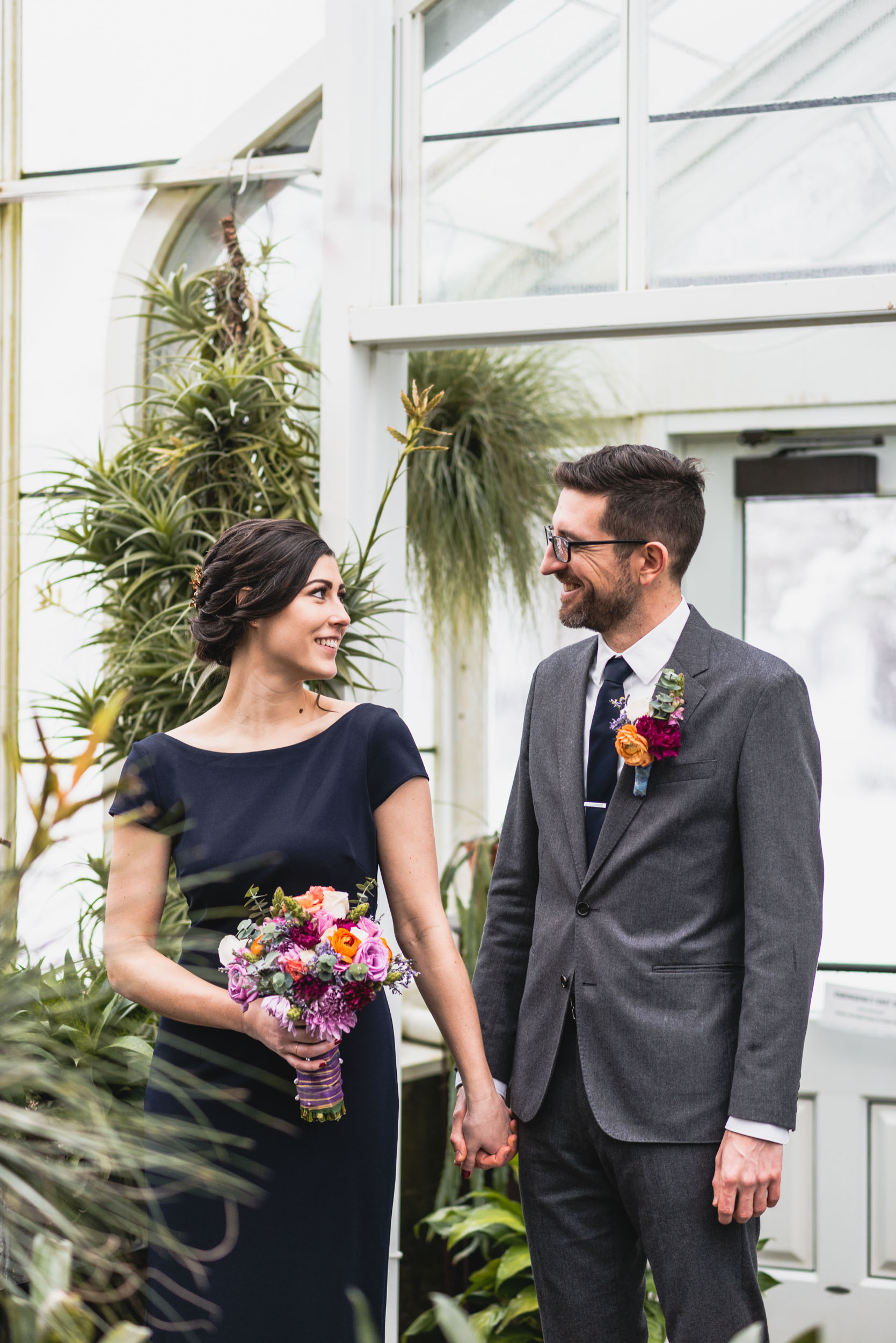 Bride and groom hold hands among plants