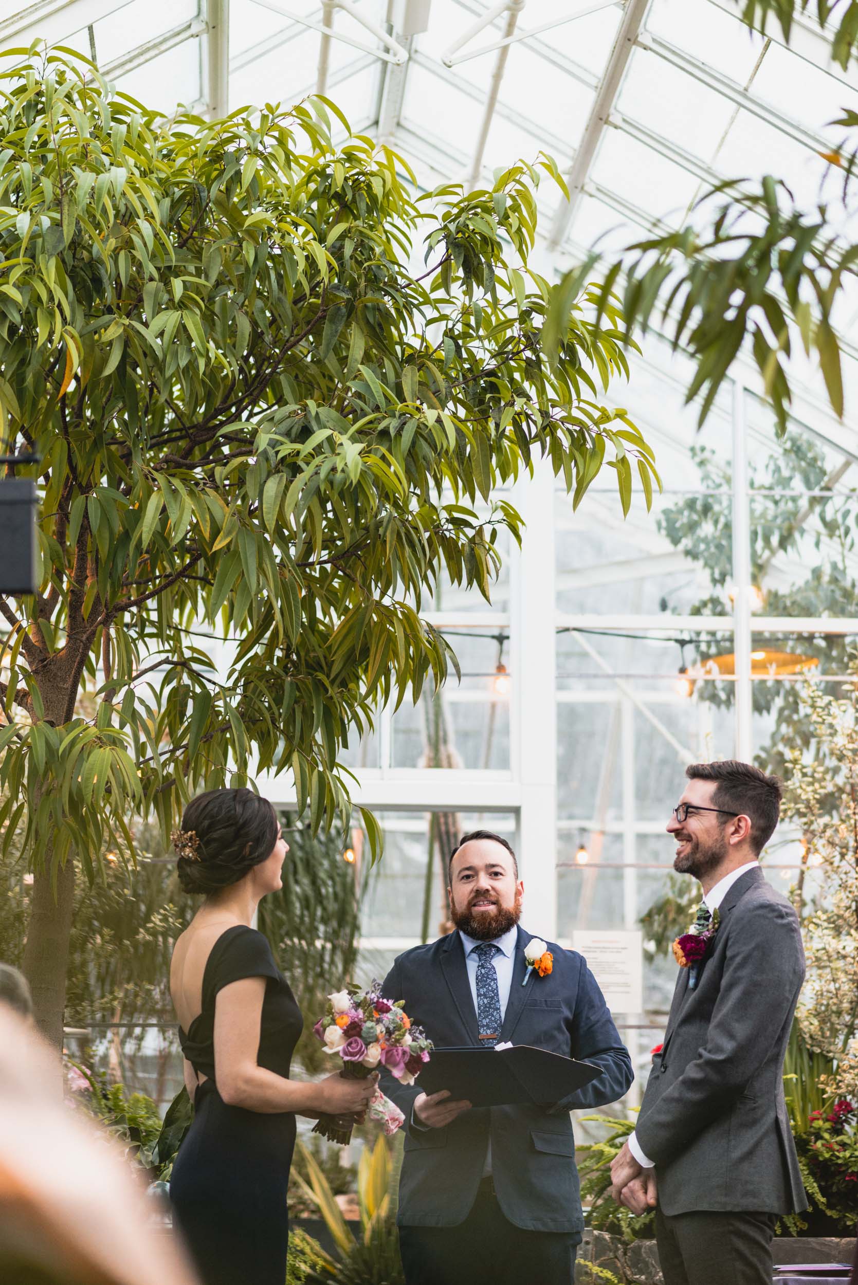 Groom, Bride and Officiant in conservatory