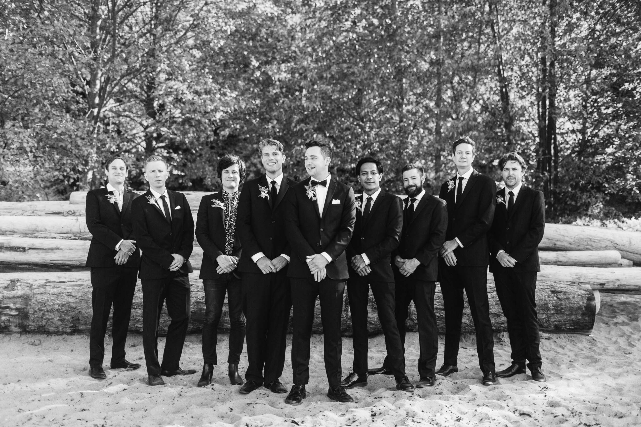 Groom and groomsmen at beach with logs