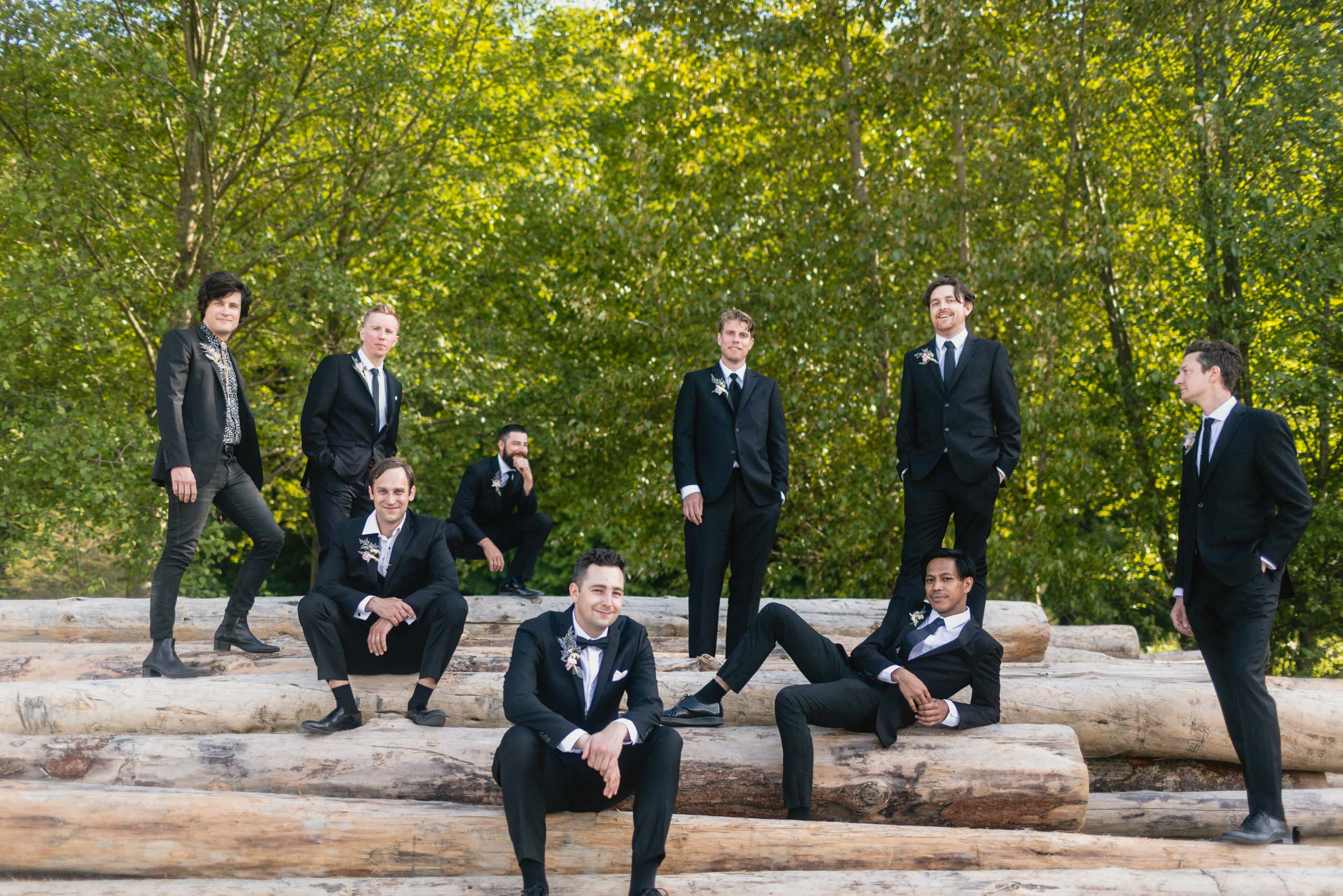 Groom and groomsmen at beach with logs