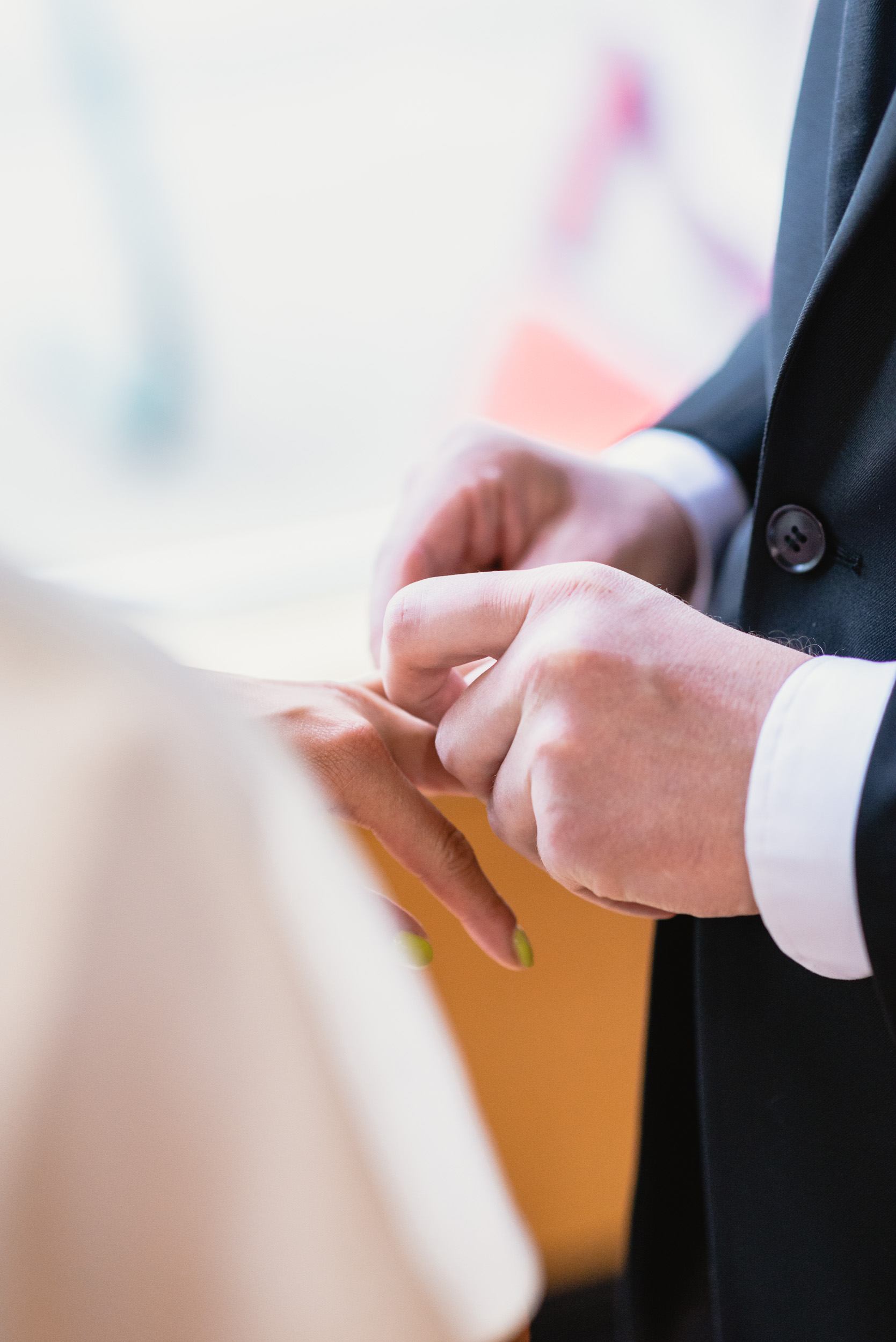 Groom putting ring on Bride's finger