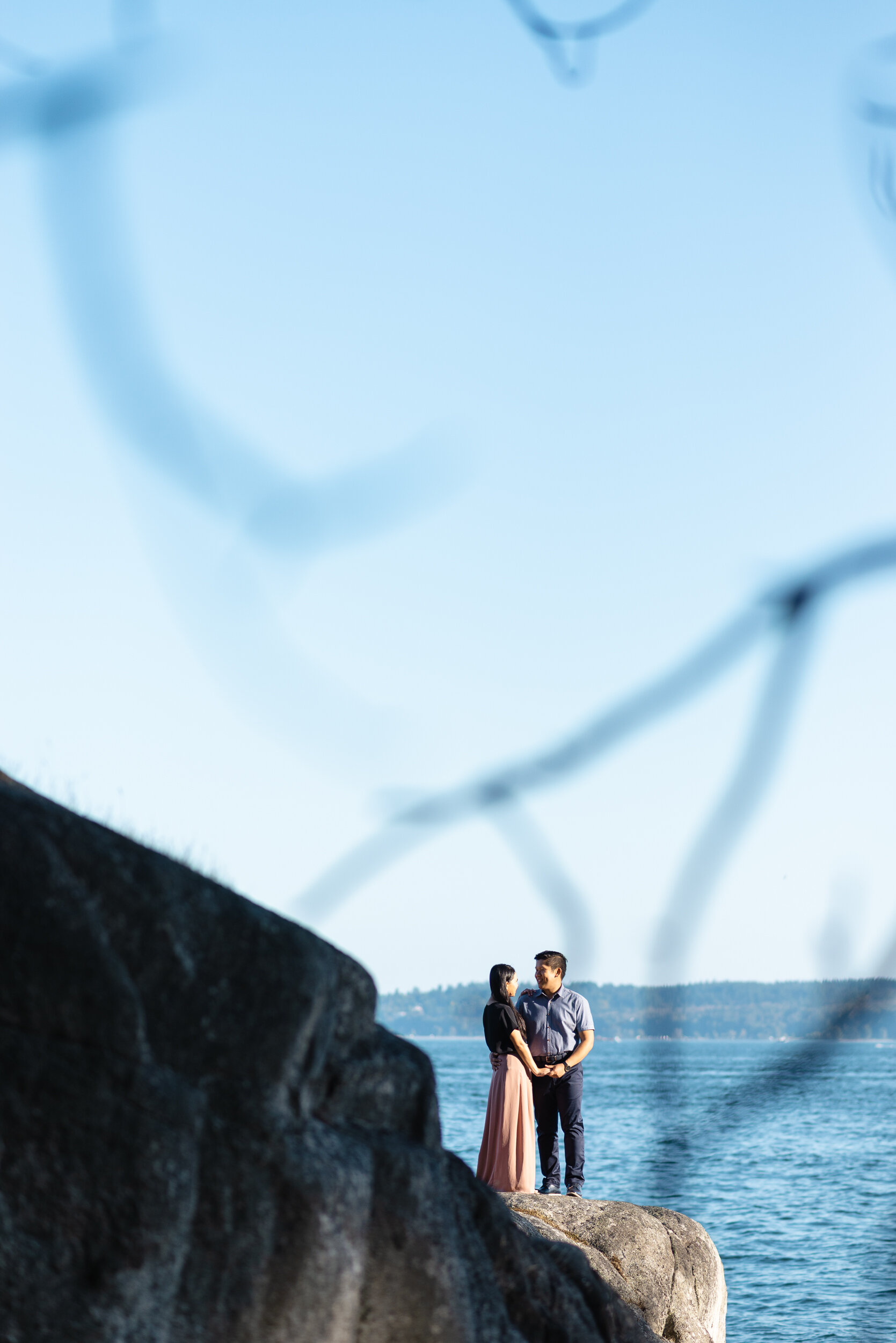 Couple stands on rock next to ocean