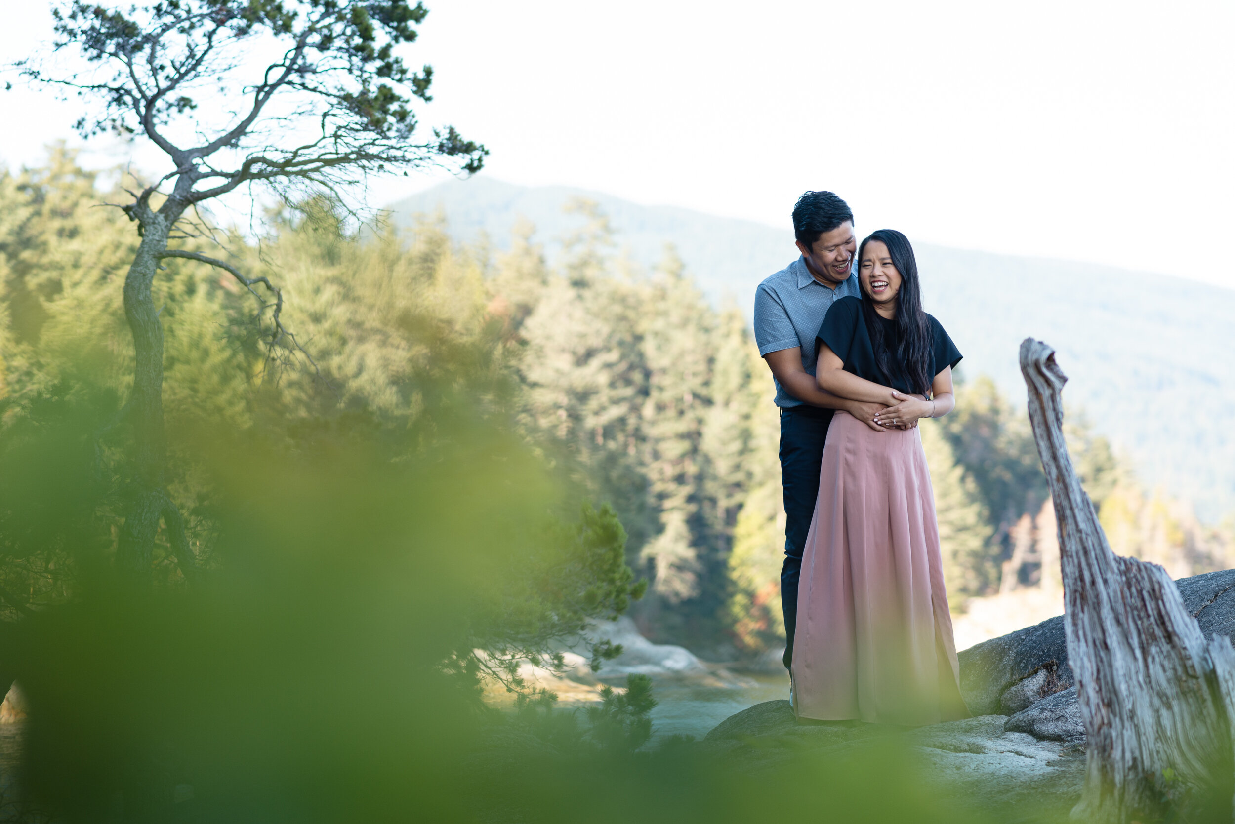 Couple embraces and laughs next to tree