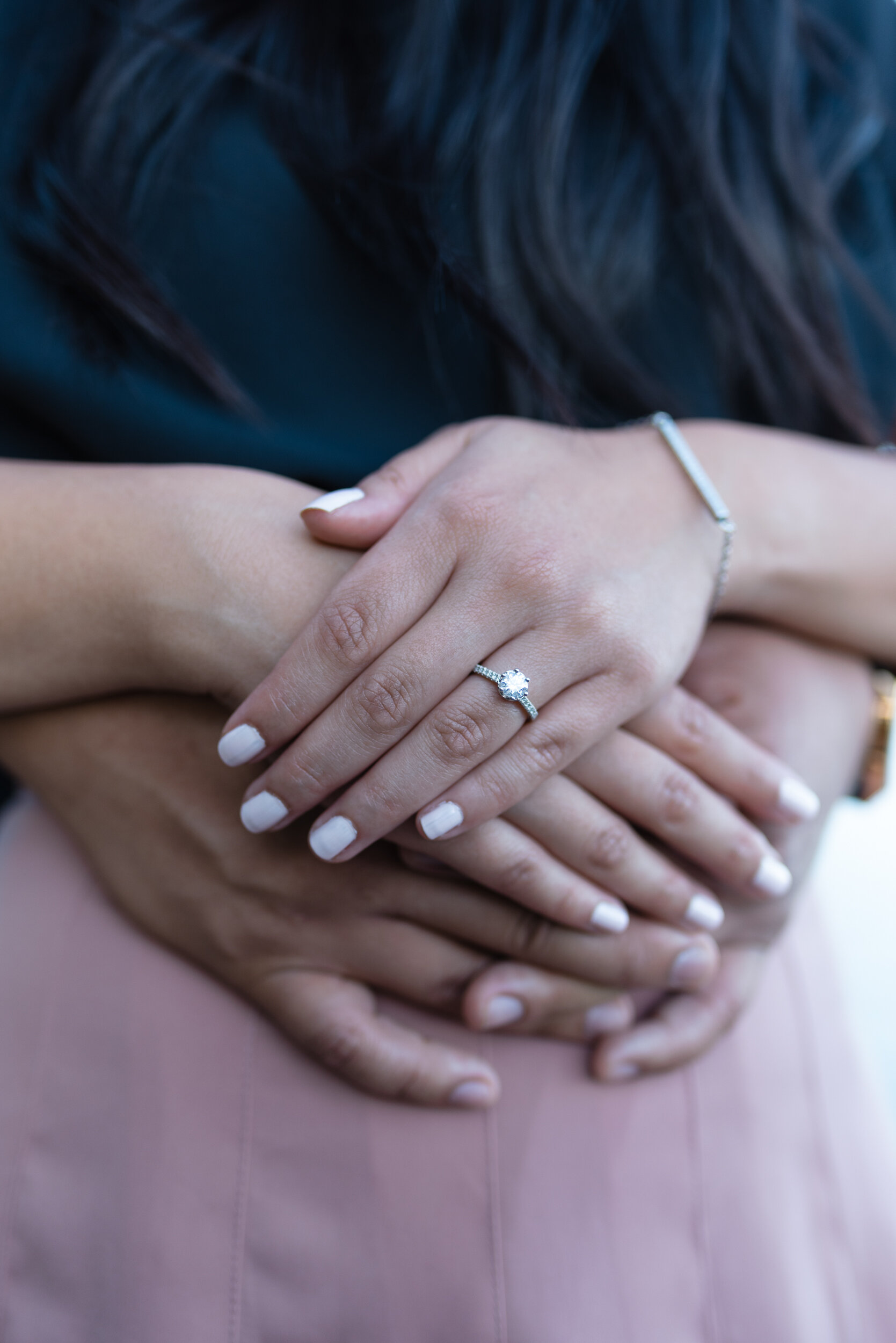 Couple's hands together showing engagement ring