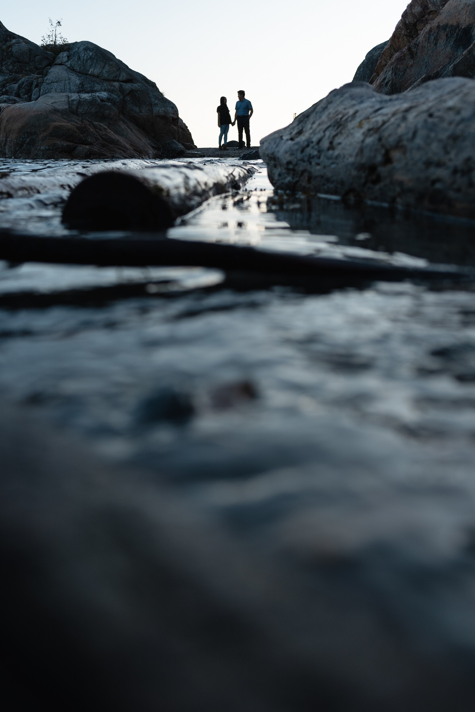 Couple between rocks at beach during sunset silhouette