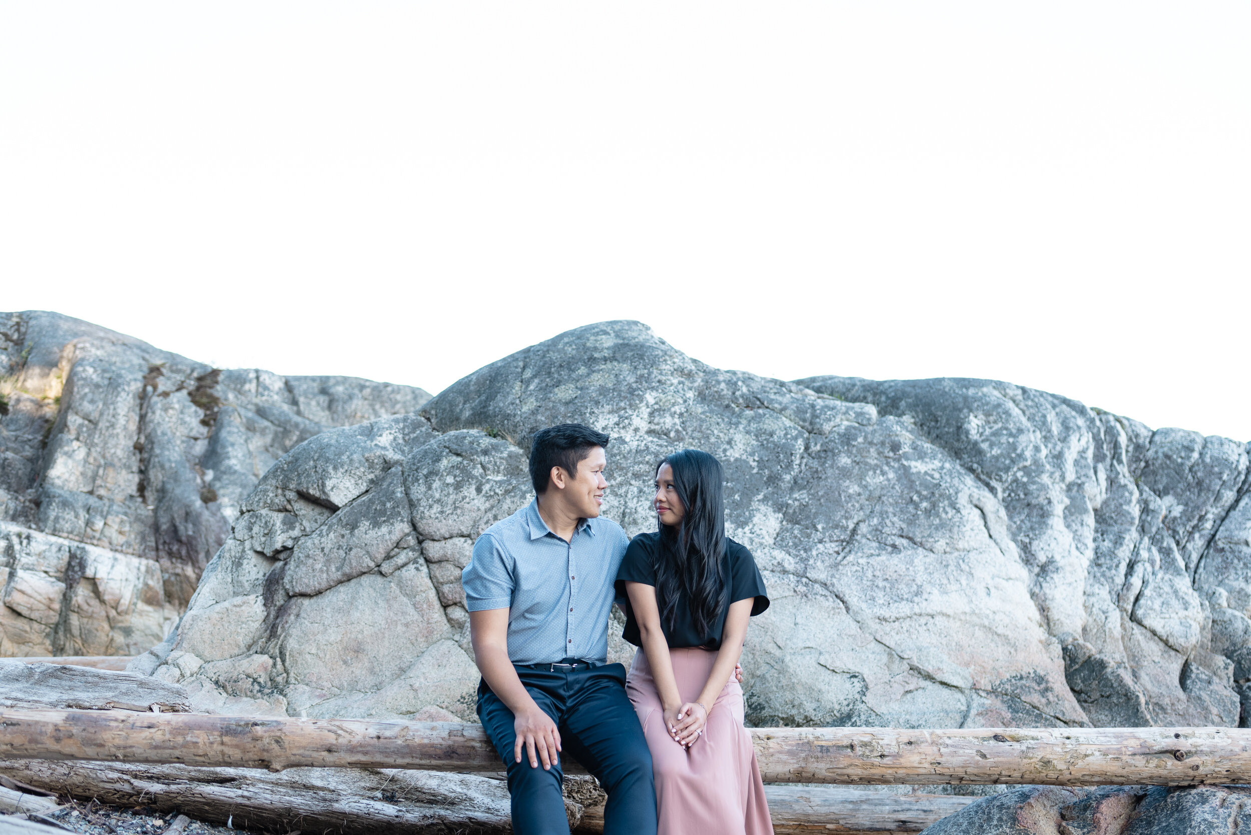 Couple sitting on driftwood at beach