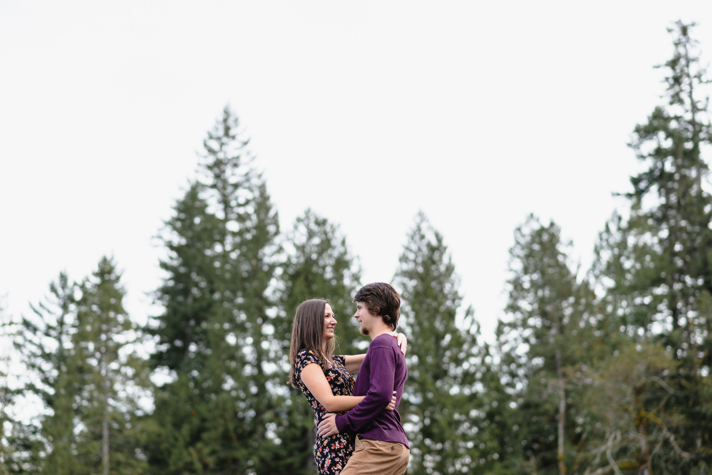 Couple embracing with trees behind them