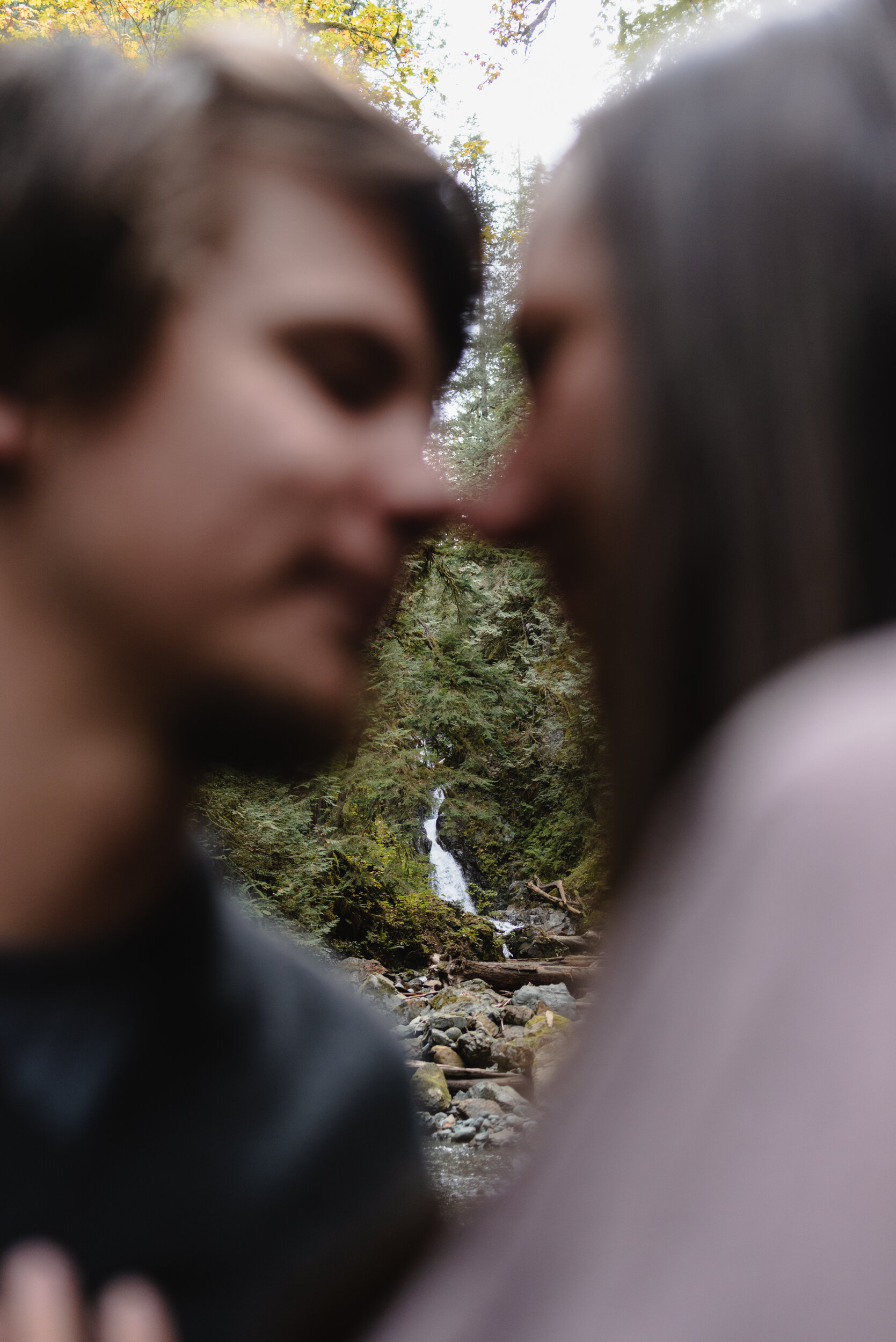 Waterfall in focus through couple's portraits