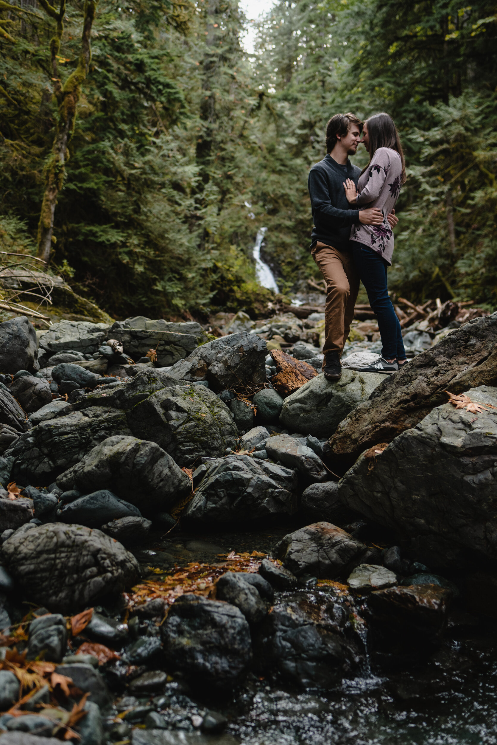 Couple standing together in creek by waterfall