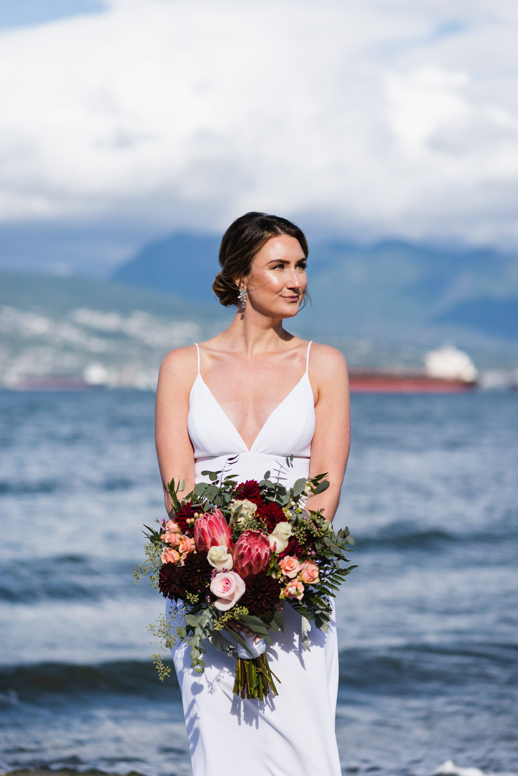 Bride standing at beach with mountains