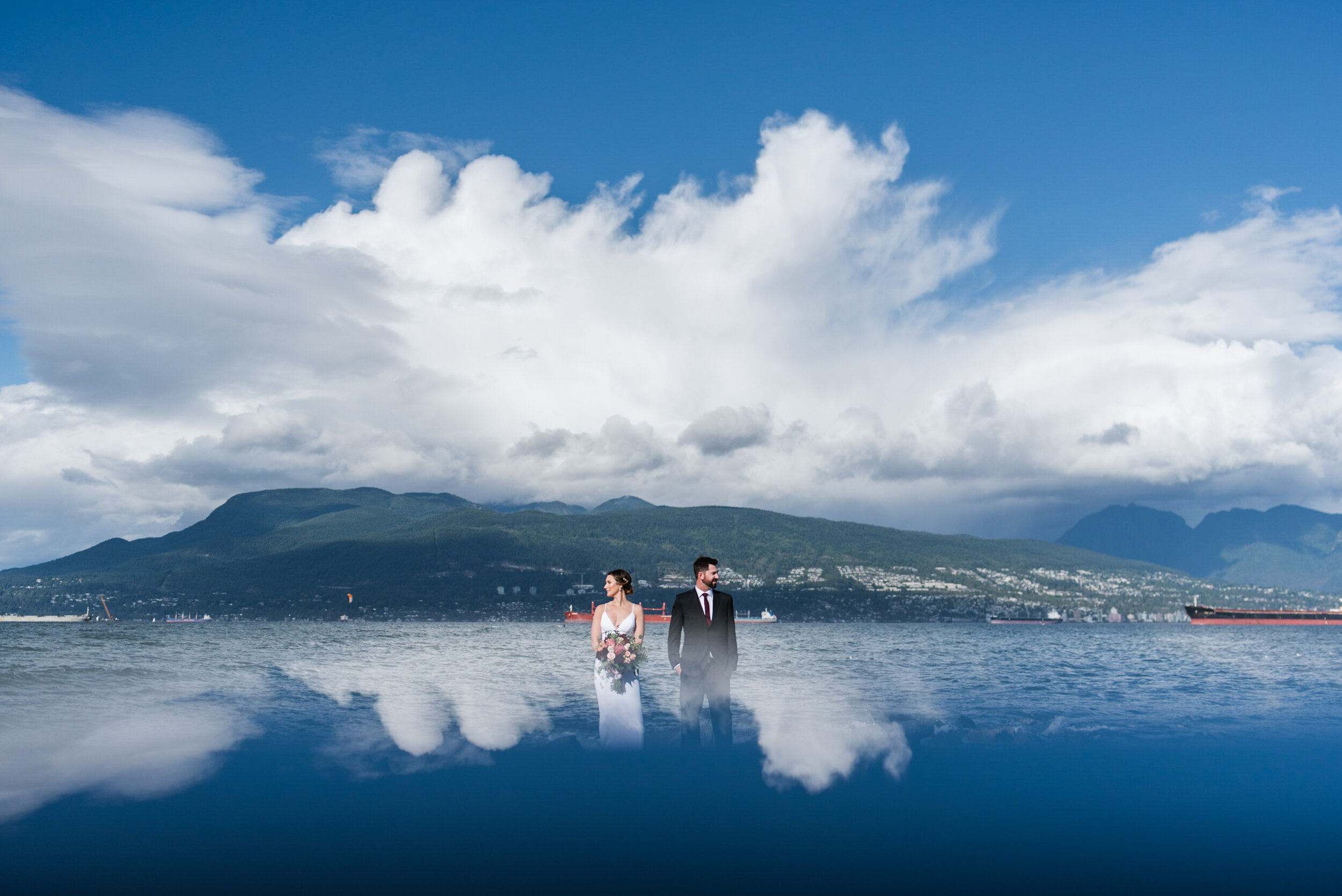 Couple standing at beach with mountains reflection