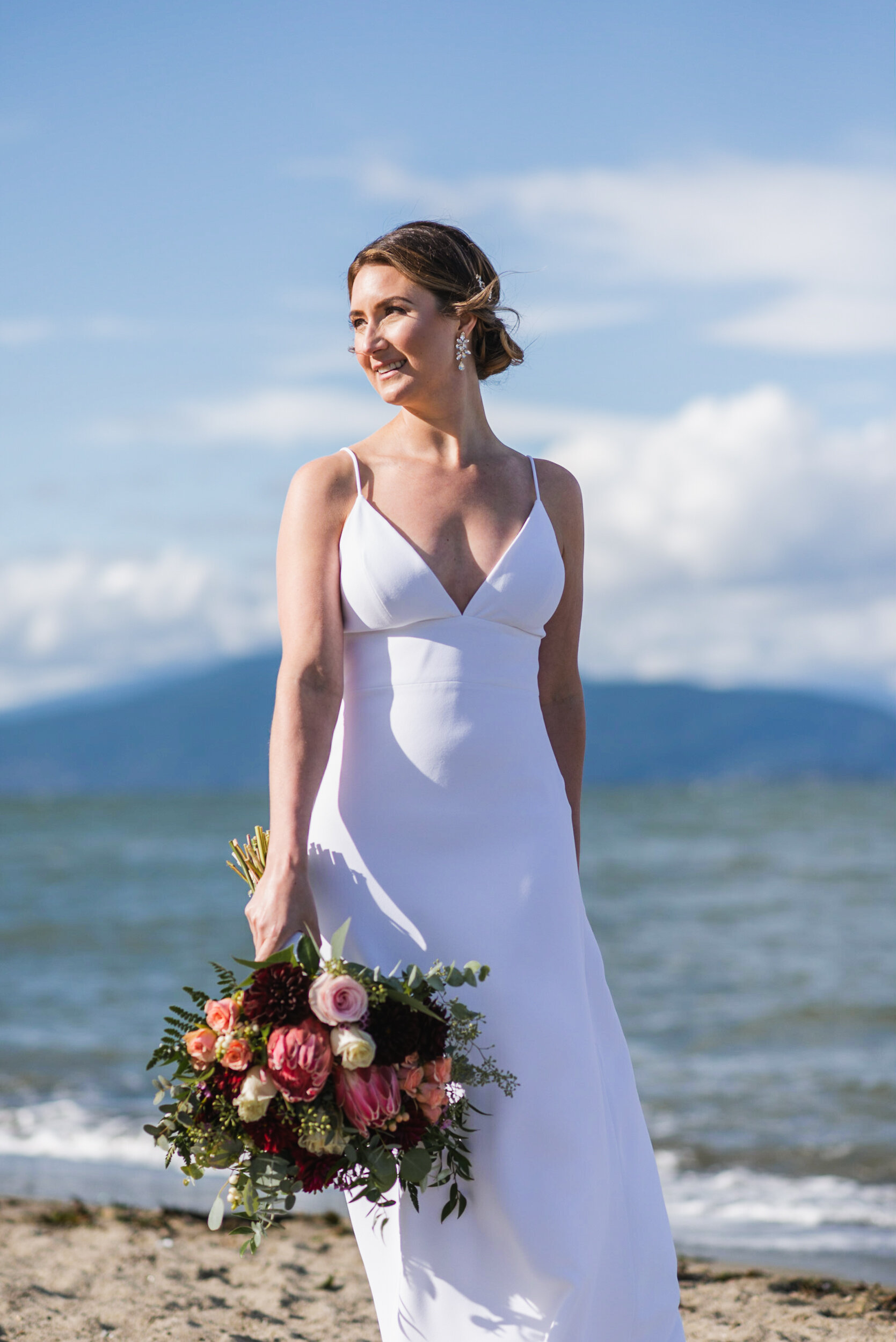 Bride standing at beach with mountains