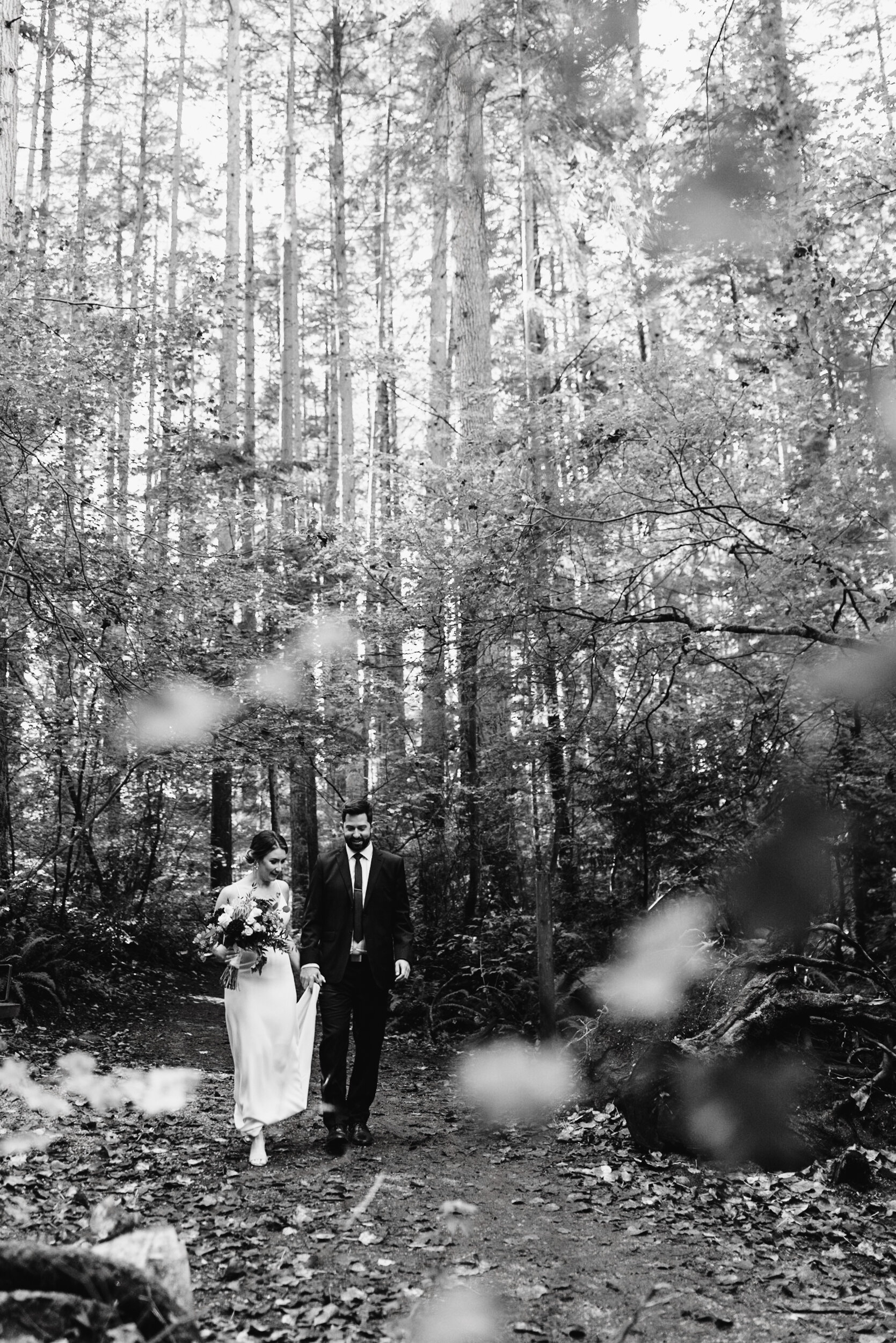 Bride and Groom walk through forest black and white