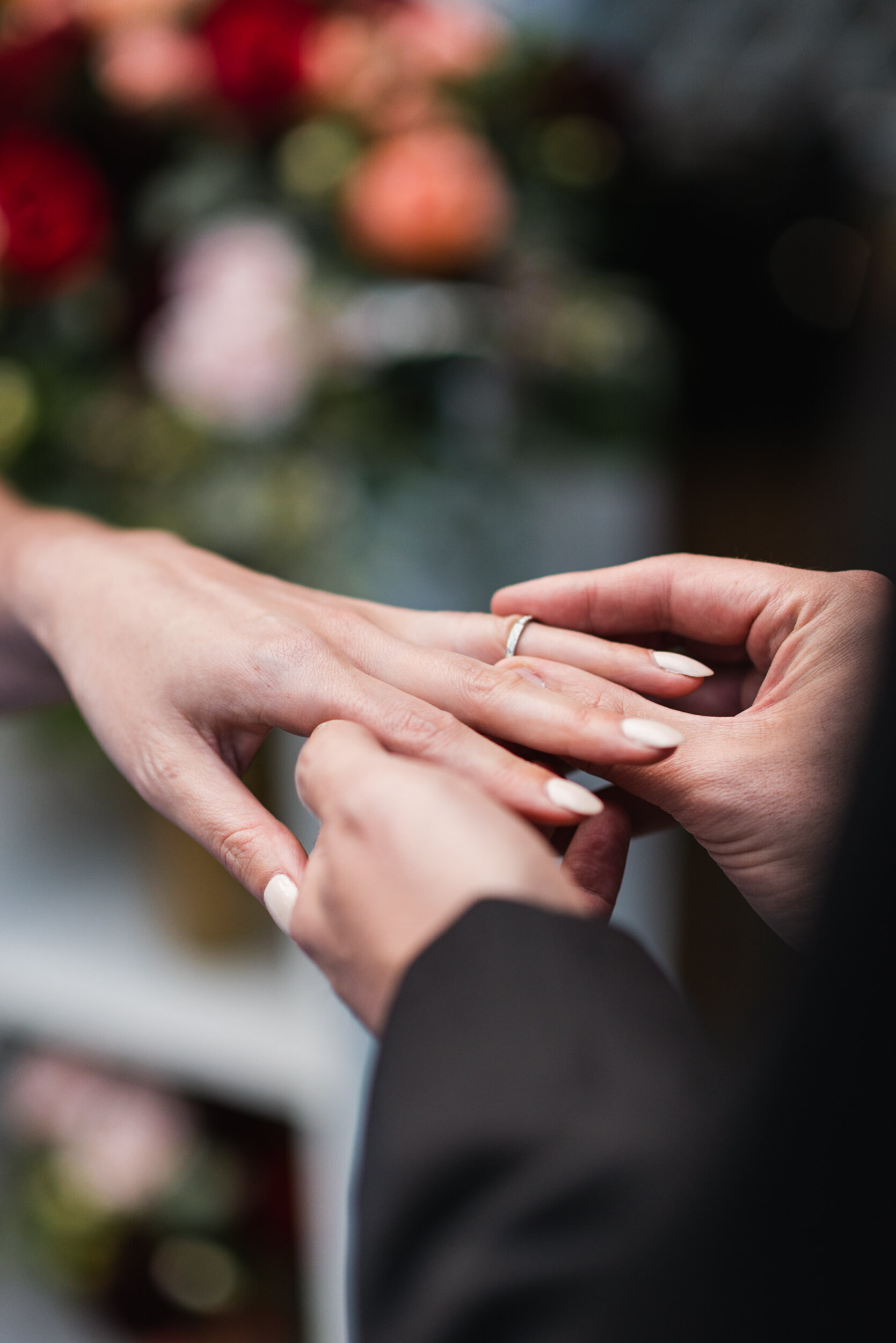 Groom places wedding ring on hand of Bride