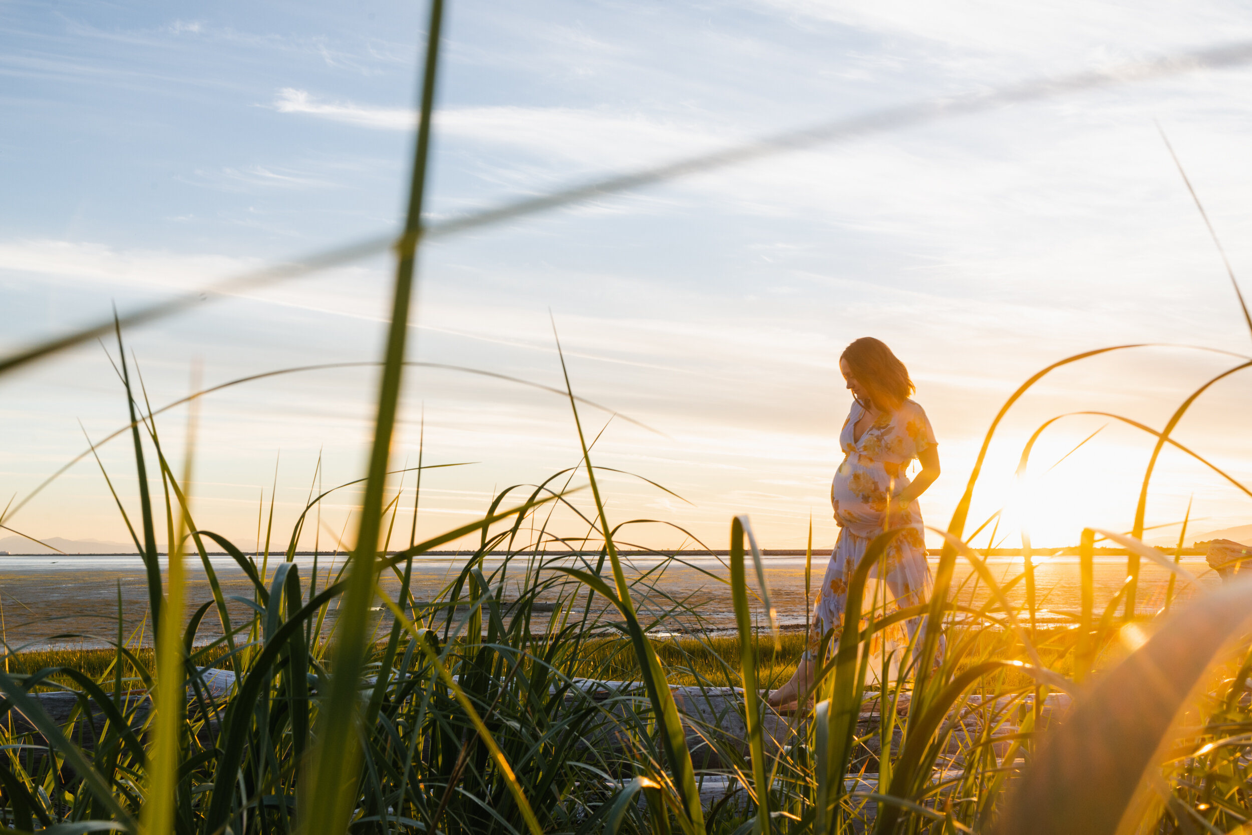 Pregnant woman beach grass sunset walking logs