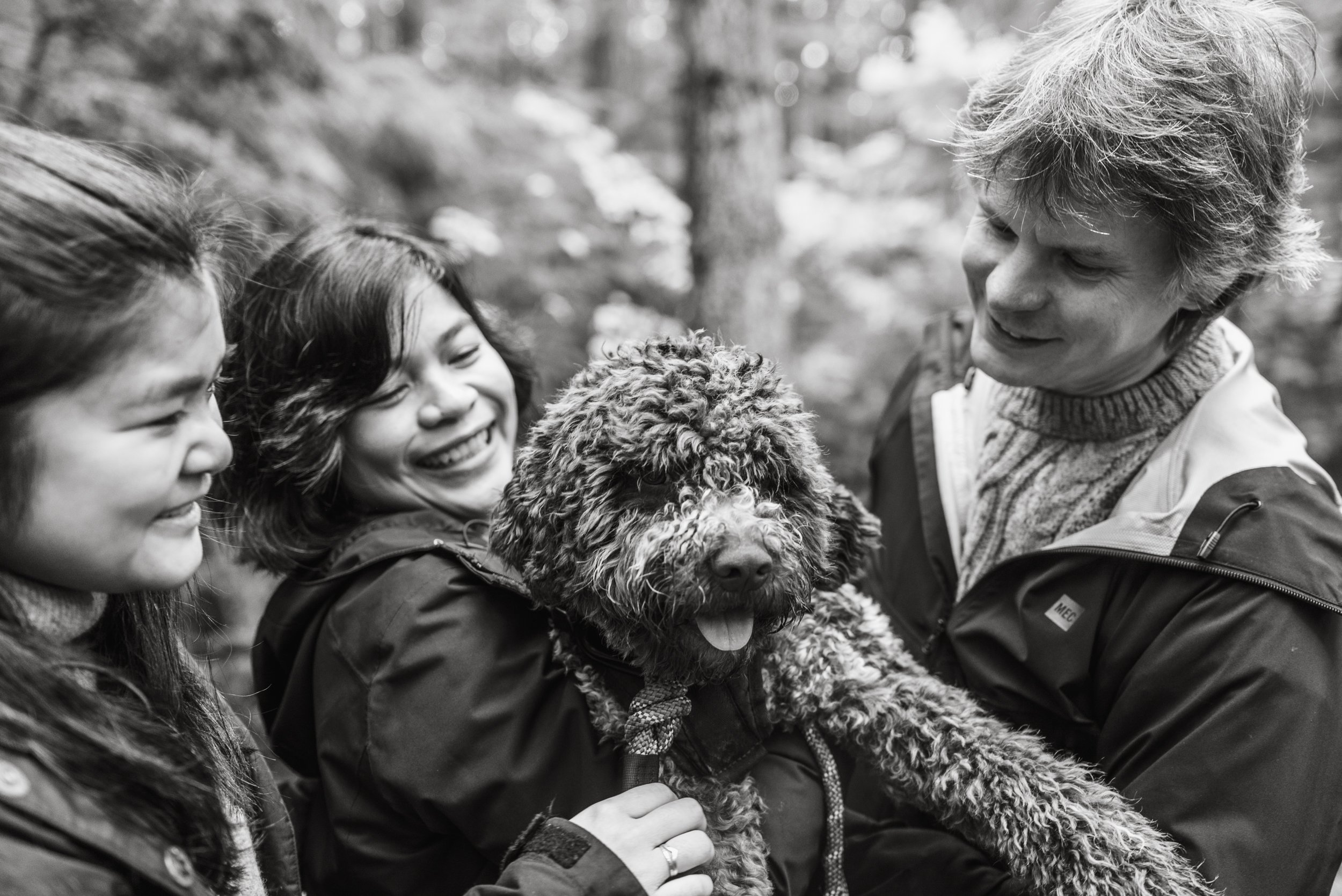 Family cuddling with dog black and white