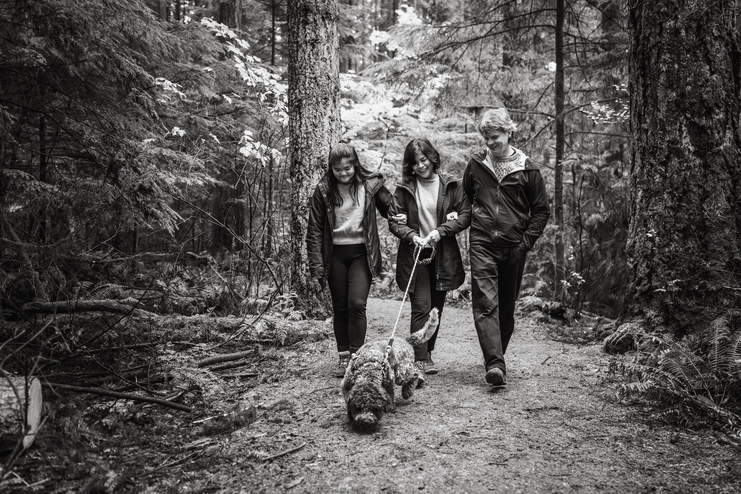 Family walking dog on forest path black and white