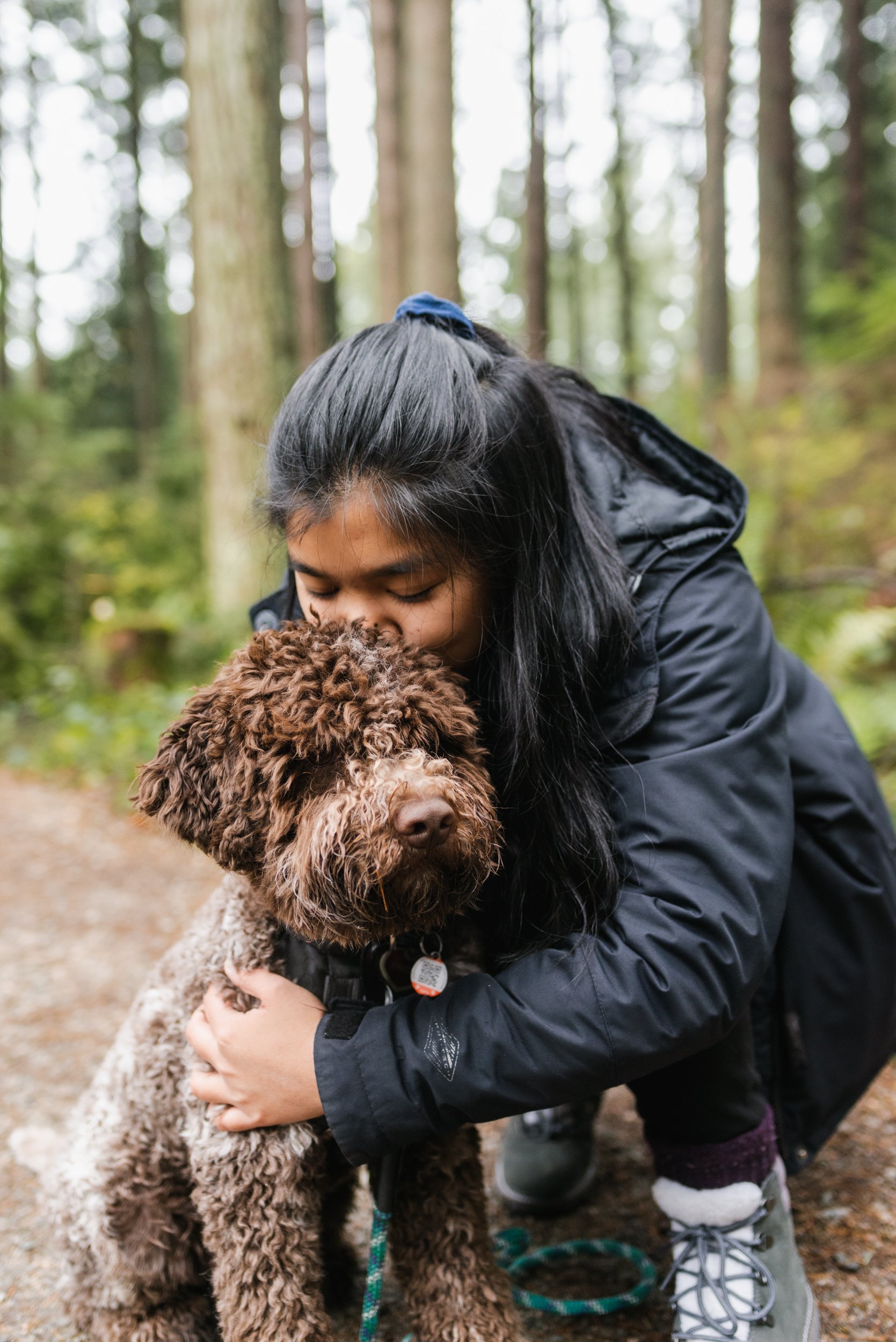 Girl kneeling and kissing dog