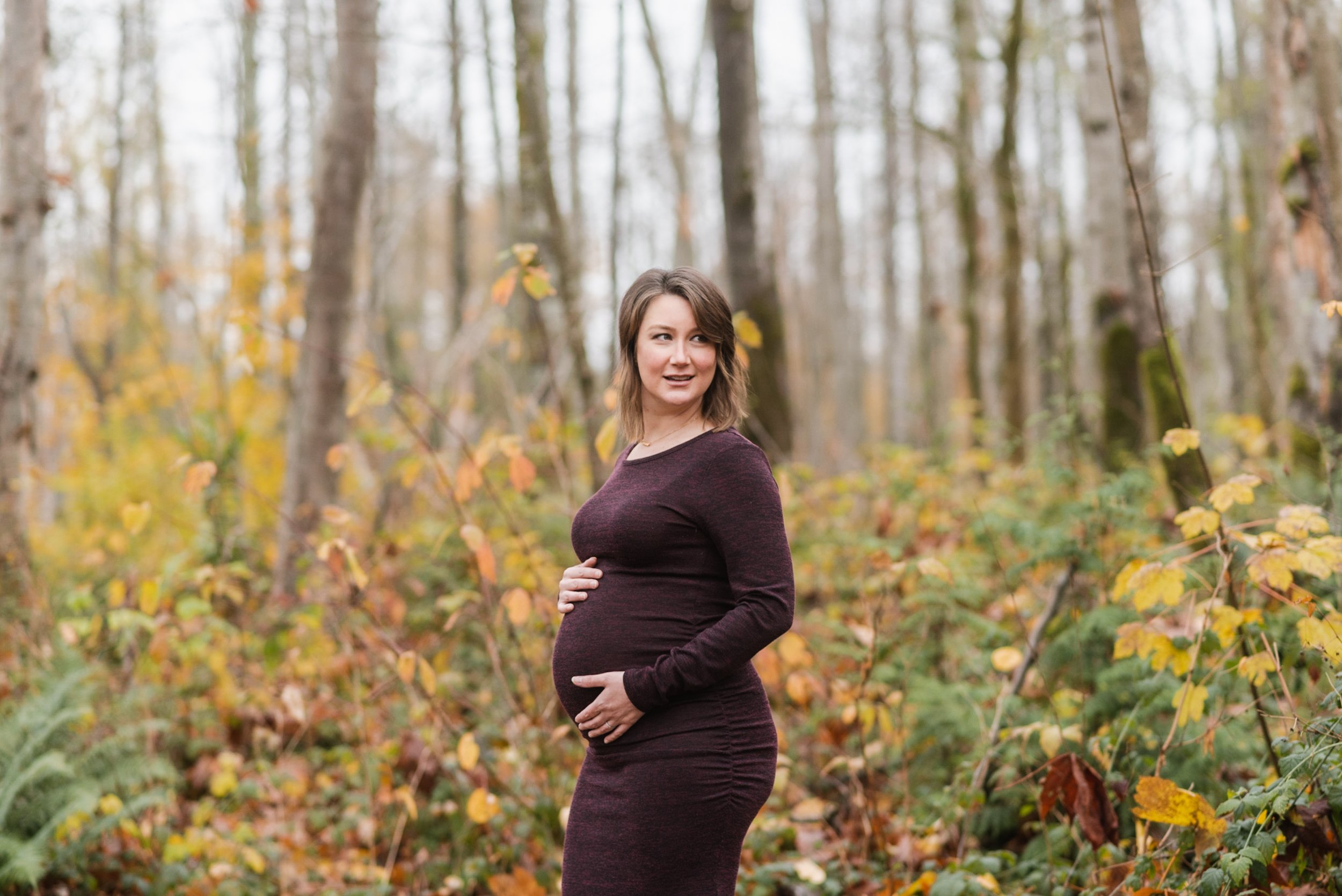 Pregnant woman burgundy dress in forest