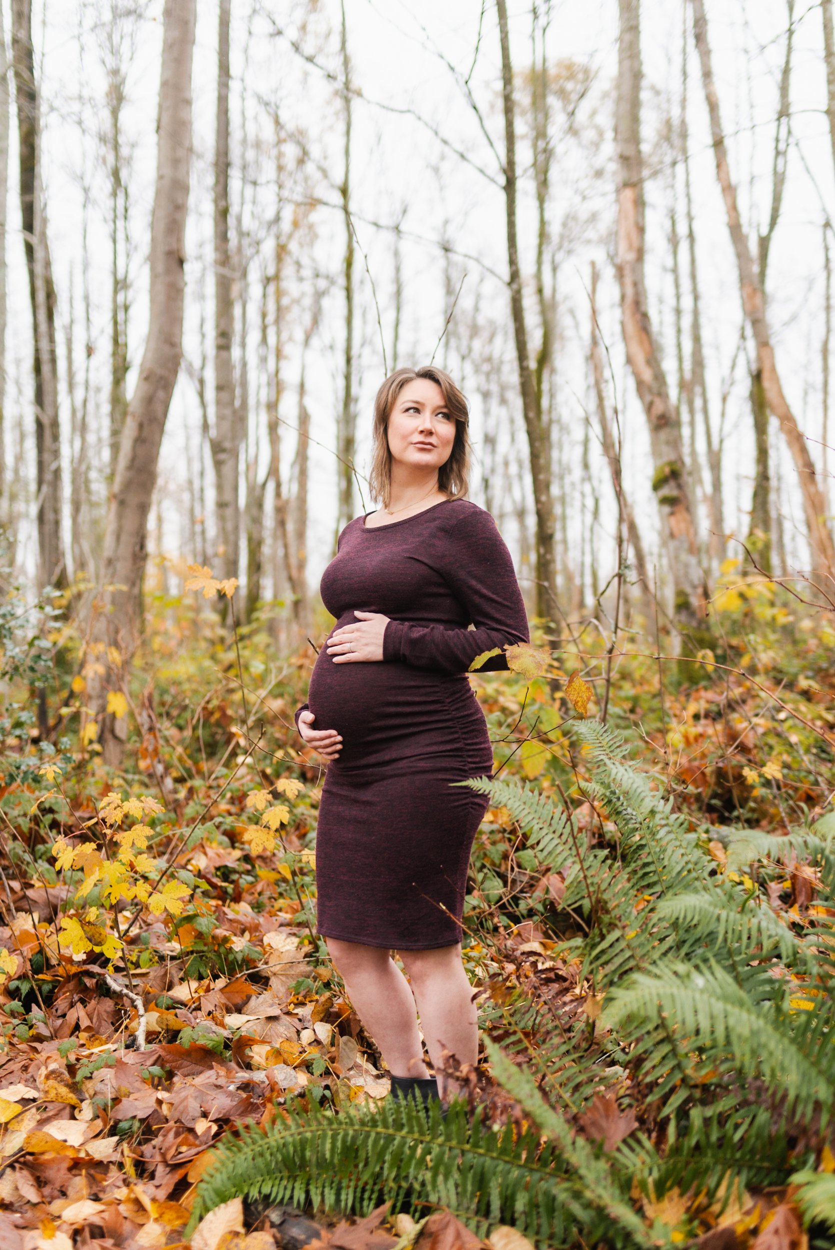 Pregnant woman burgundy dress in forest