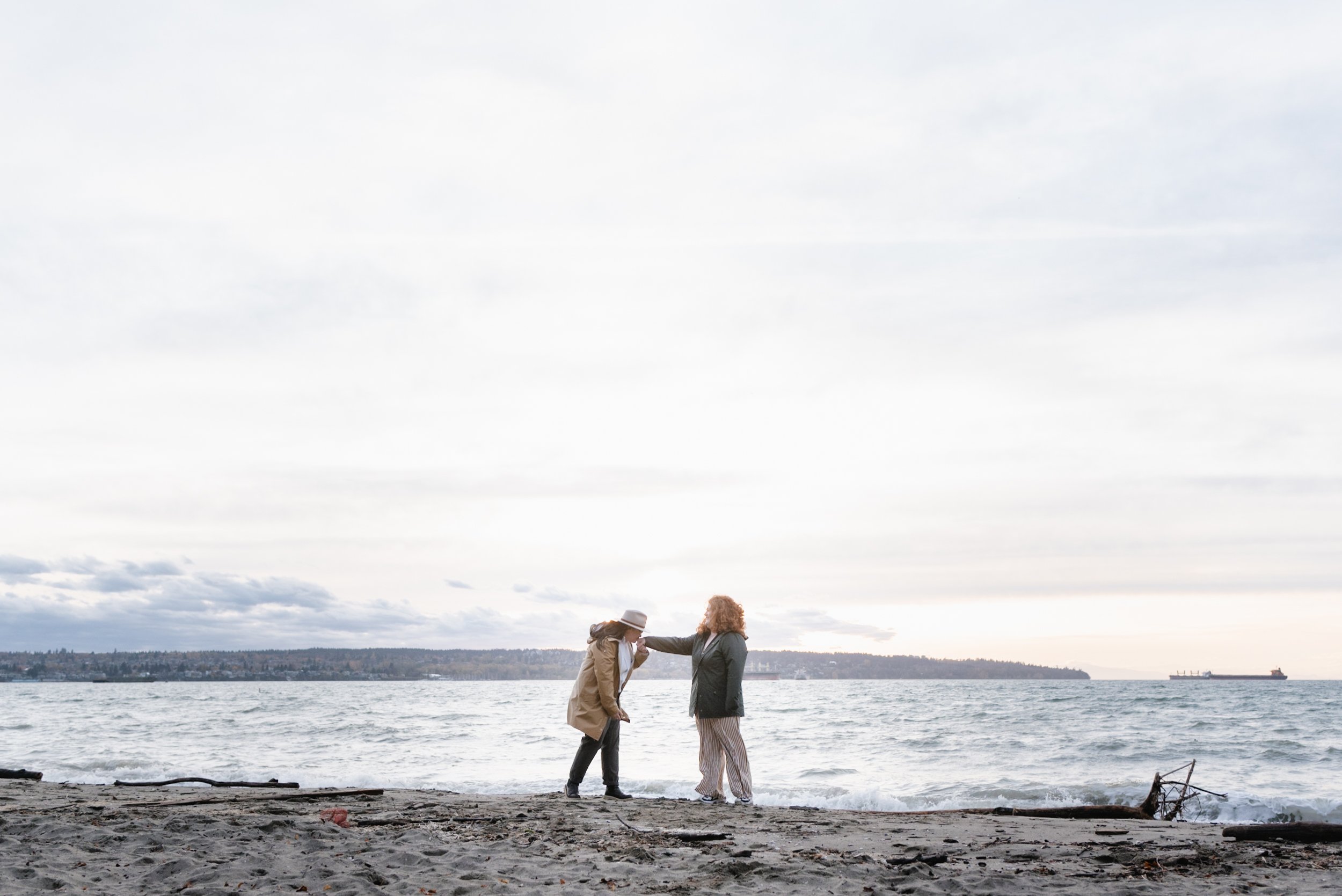 Wide shot of couple kissing hands at Stanley Park's Second Beach